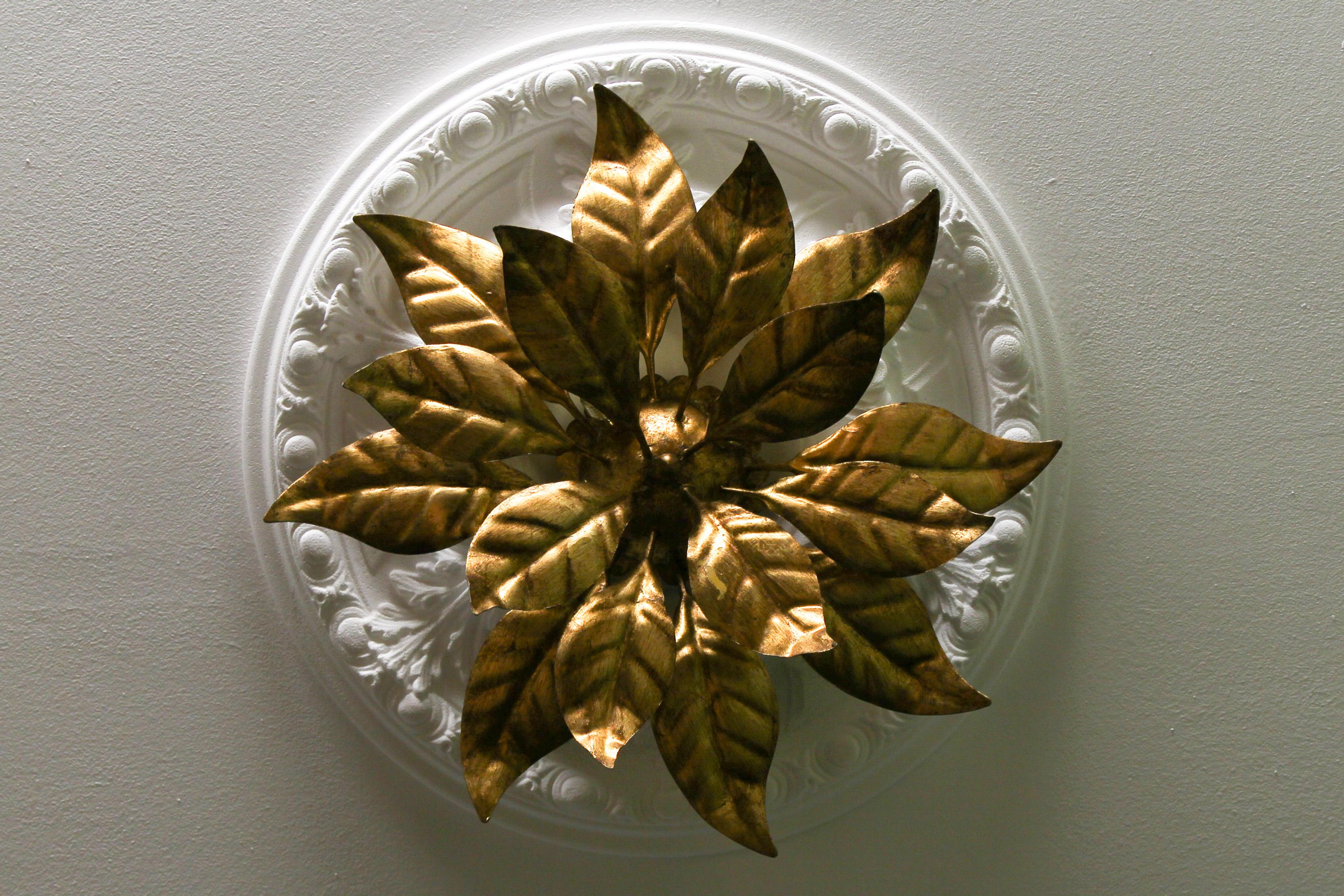 This gorgeous Hollywood Regency-style ceiling lamp is made of gilt metal and has four lights. It features beautifully sculpted golden leaves that form the shape of a large flower. The light fixture can be used as either a wall sconce or ceiling