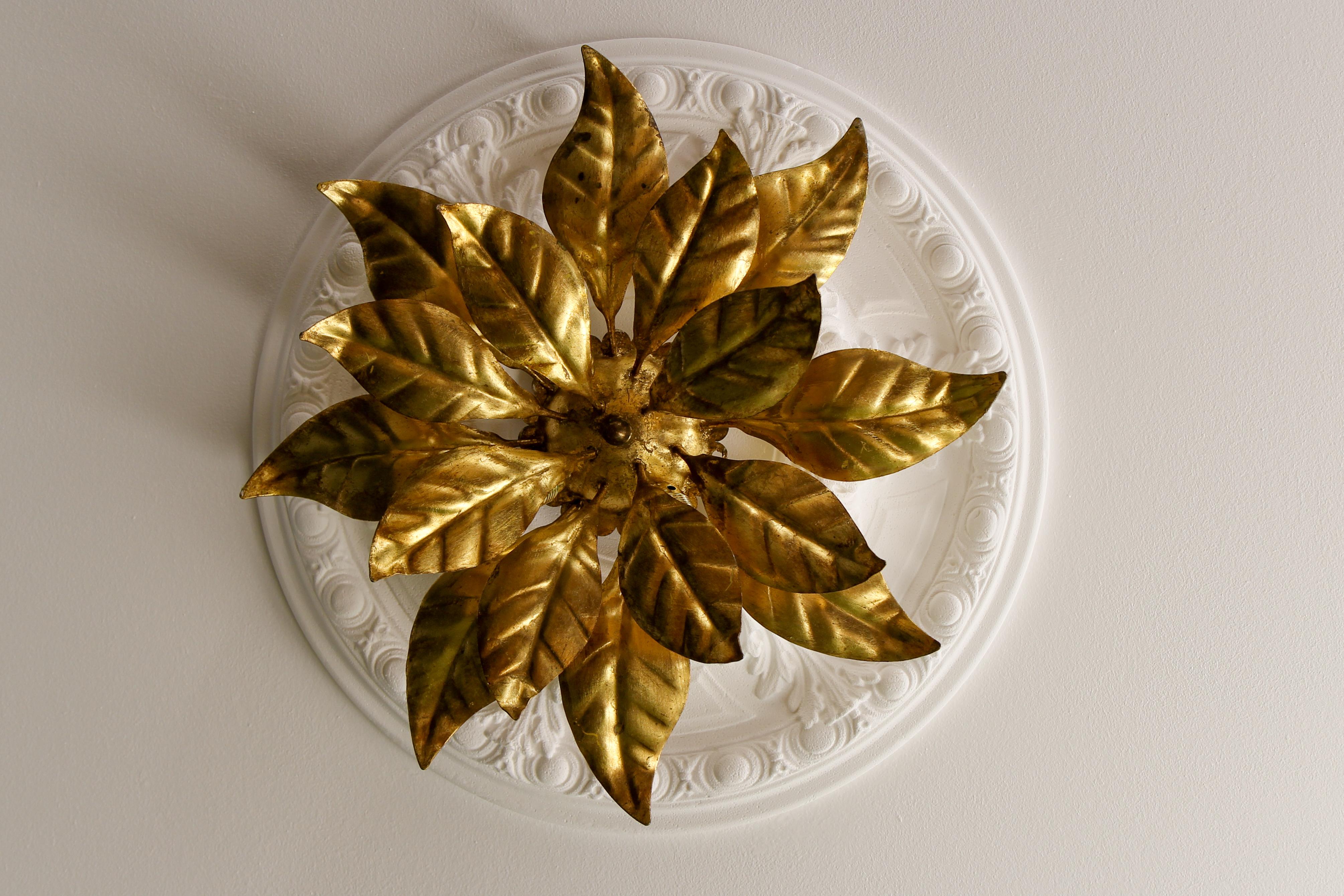 This gorgeous Hollywood Regency-style ceiling lamp is made of gilt metal and has four lights. It features beautifully sculpted golden leaves that form the shape of a large flower. The light fixture can be used as either a wall sconce or ceiling