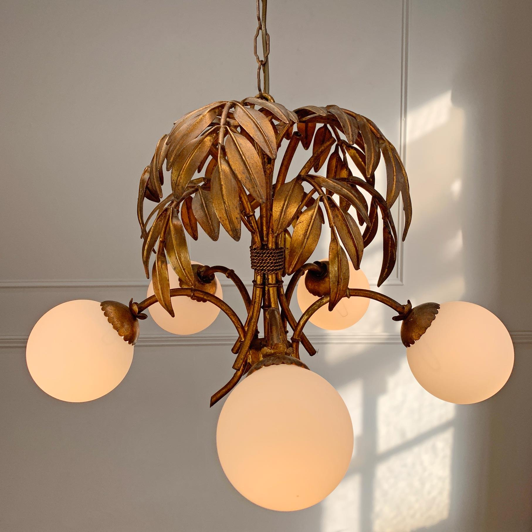 Stupendo lampadario Hans Kogl in bronzo dorato risalente agli anni '70, con baldacchino in foglie di bambù dorate e bracci in finto bambù, ciascuno dei quali ospita un singolo portalampada e14 (a vite piccola), che si trova sotto paralumi a globo in
