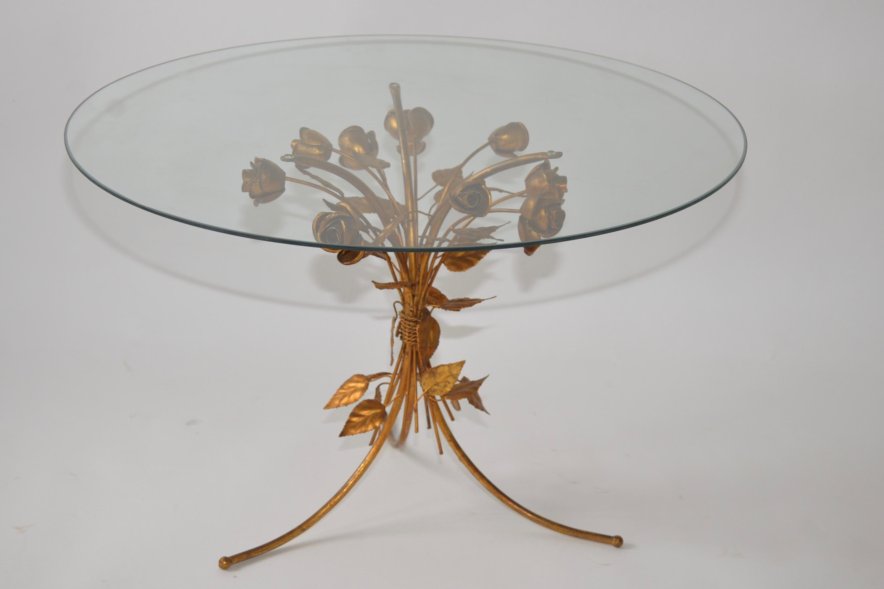 A Hans Kögl Hollywood Regency side table that features gold gilt metal tripod base of flowers and leaves with a glass top. This is a lovely intricate piece from the well-known and well documented German designer.