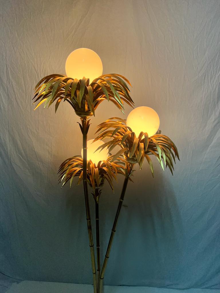 Preciosa lampara palmera de 3 brazos de latón con 3 luces en palmas de palmera con una bola de cristal de opalina blanco en el centro.