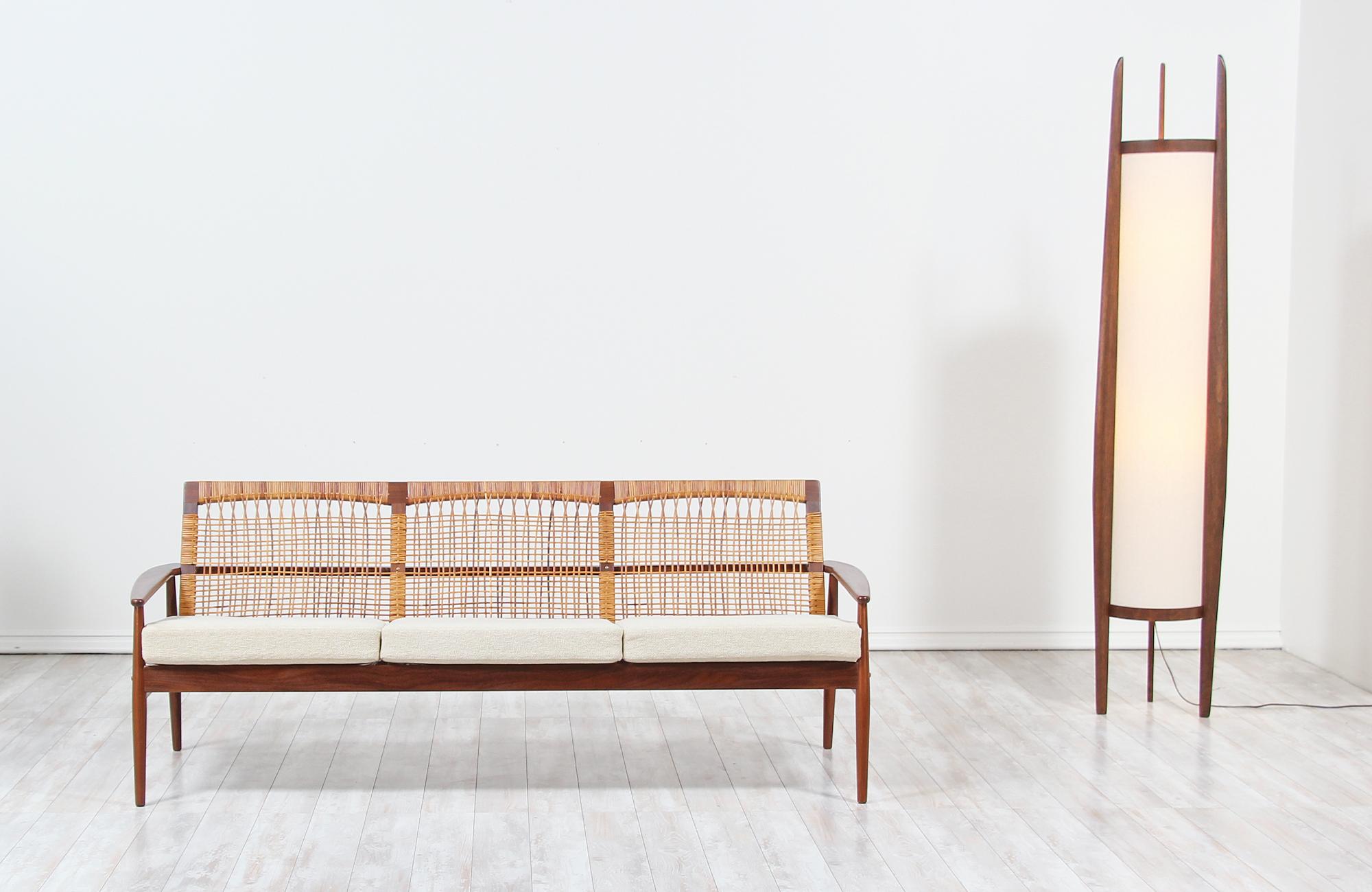 Striking 3-seat sofa designed by Hans Olsen for Juul Kristensen in Denmark, circa 1960s. This stylish design features a sturdy teak wood frame with its original cane backrest and new springs to ensure comfortable support while keeping the modern