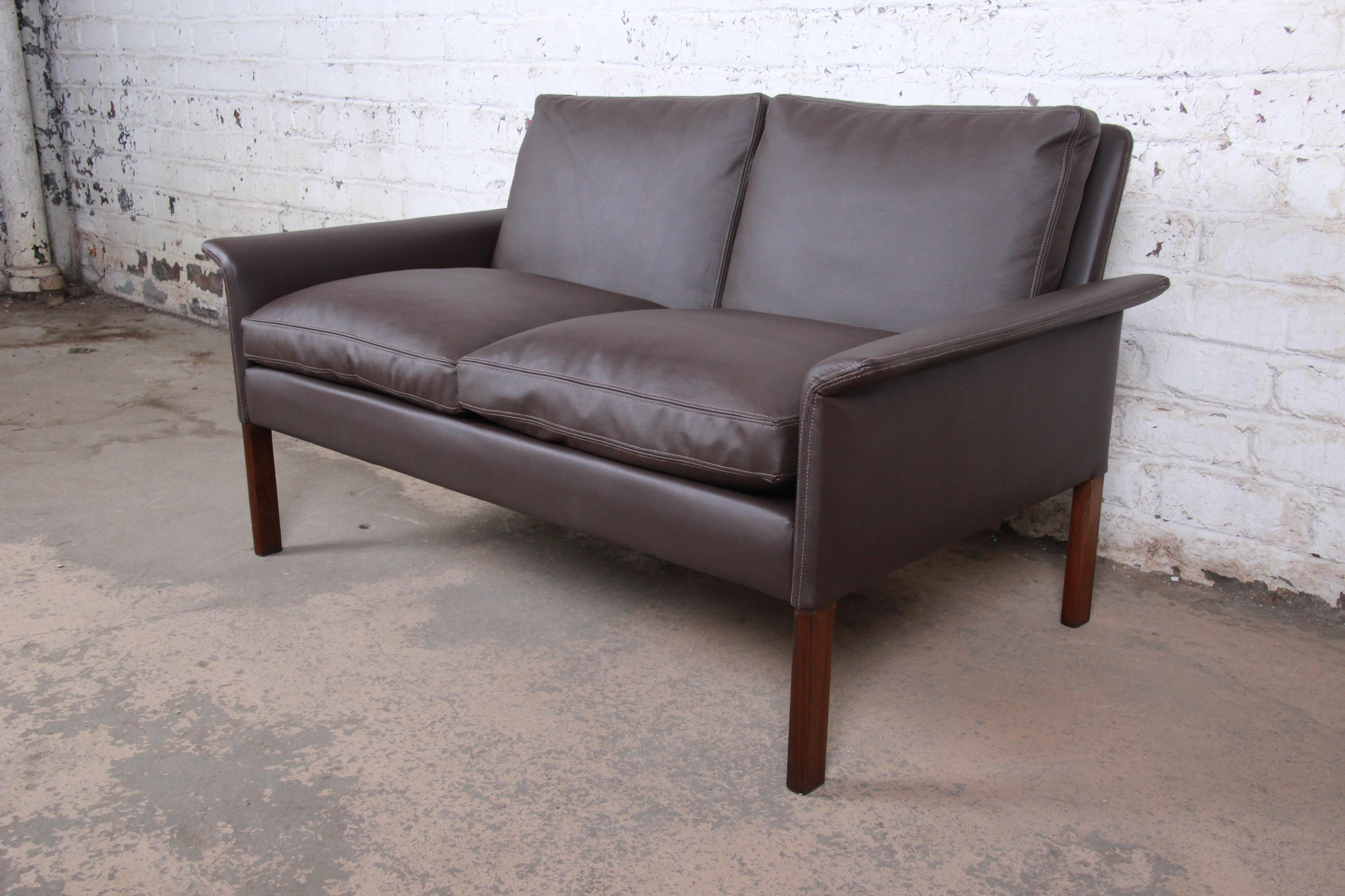 An exceptional midcentury Danish modern settee or loveseat

Designed by Hans Olsen for Christian Sorensen

Denmark, 1960s

Brown leather and rosewood and down-filled cushions

Measures: 51.13