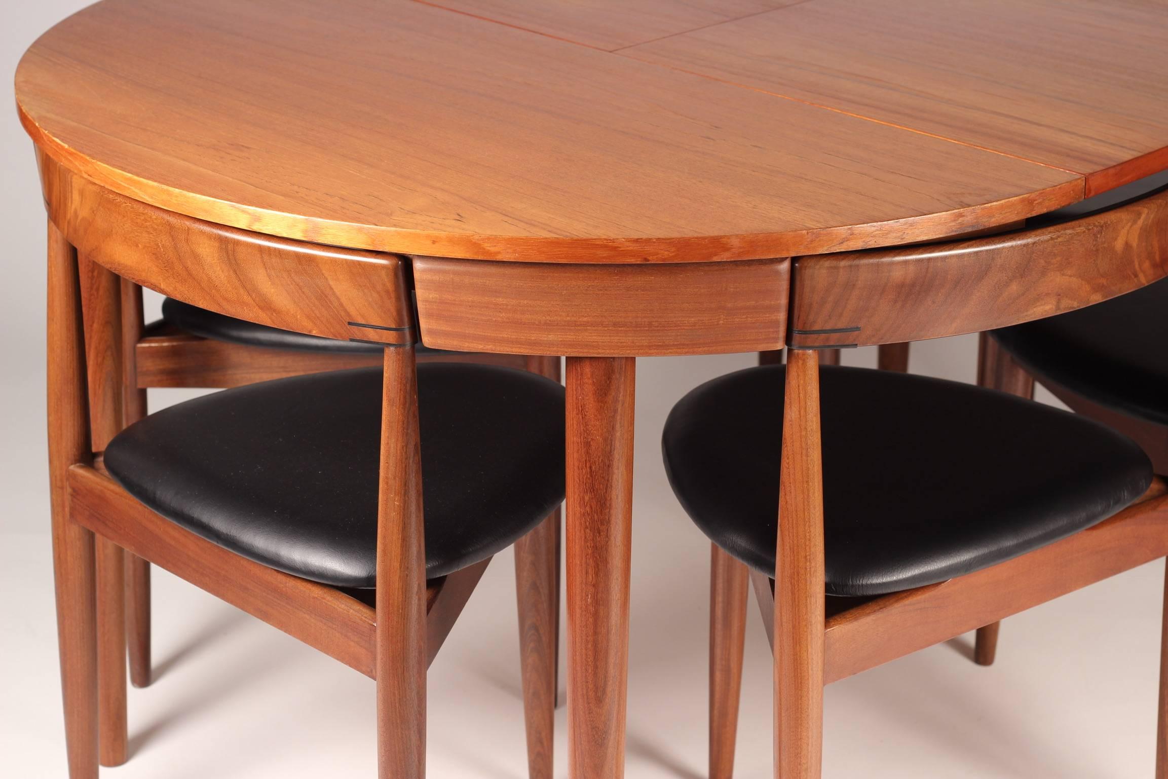 Scandinavian Modern designed, rare teak and leather model Roundette dining table and six chairs. The table expands from a round that accommodates four chairs neatly tucked around its outer rim, up to an expansive roundel which you can then pull up