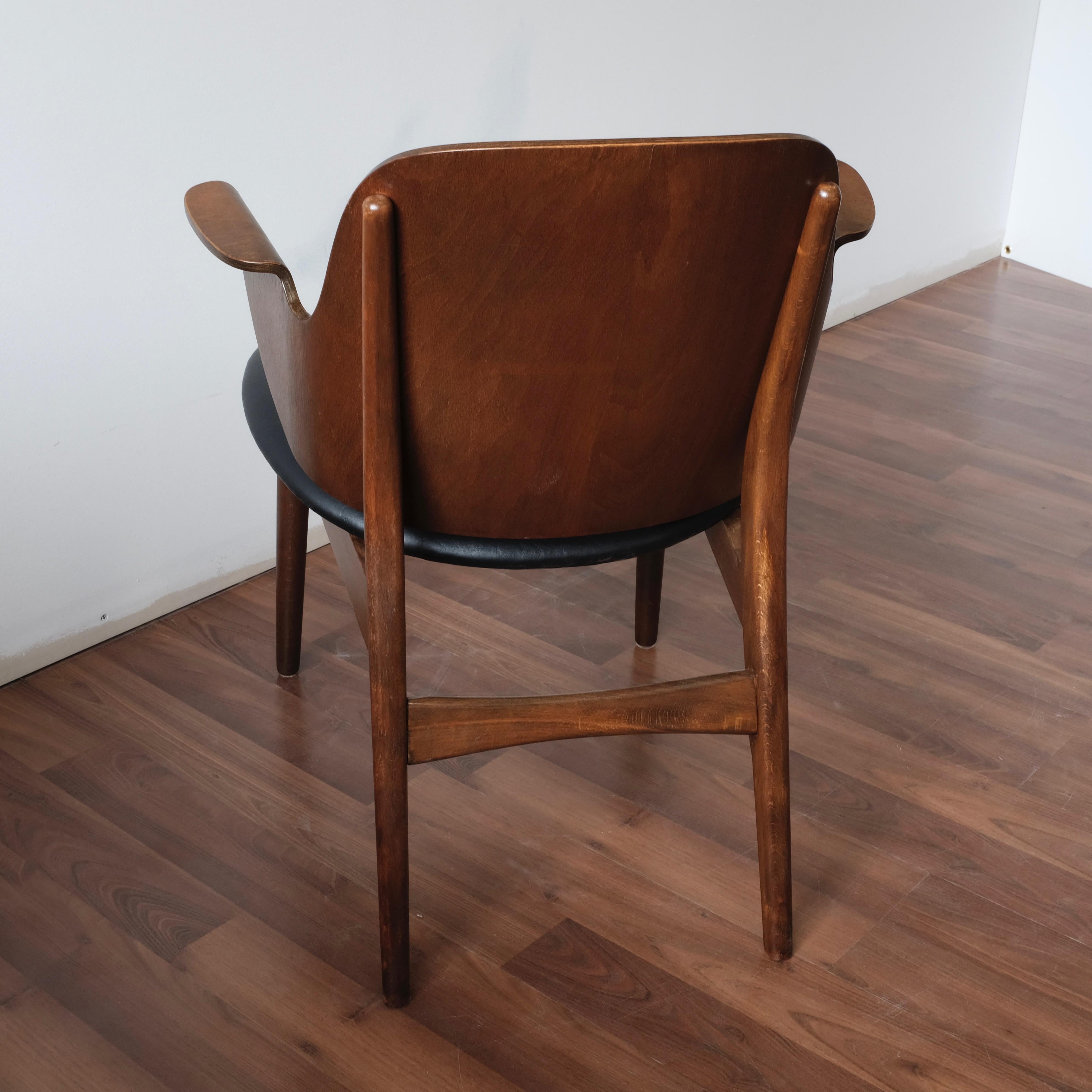 Model 107 armchair designed by Hans Olsen and made in Denmark by Bramin Møbler.

Solid beech frame with bent plywood shell seat and back with integral armrests, finished in a teak/walnut stain. Seat and back reupholstered with black leatherette.