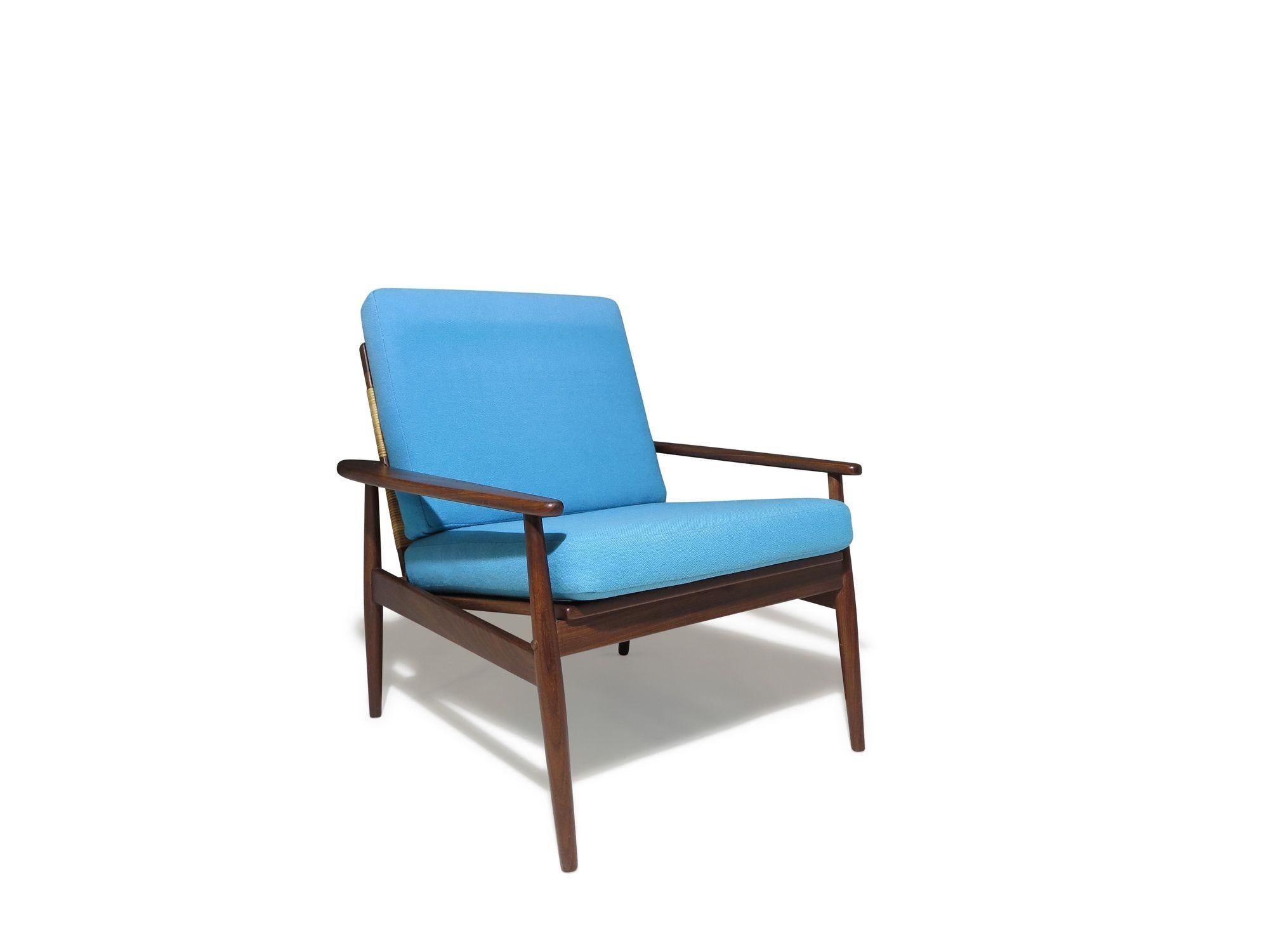 Sillón moderno de mediados de siglo diseñado por Hans Olsen, con estructura de madera, respaldo de caña tejida y cojines tapizados en tela de lana azul vintage. La combinación de ricos tonos de madera, tejido de caña natural y tapicería le confiere