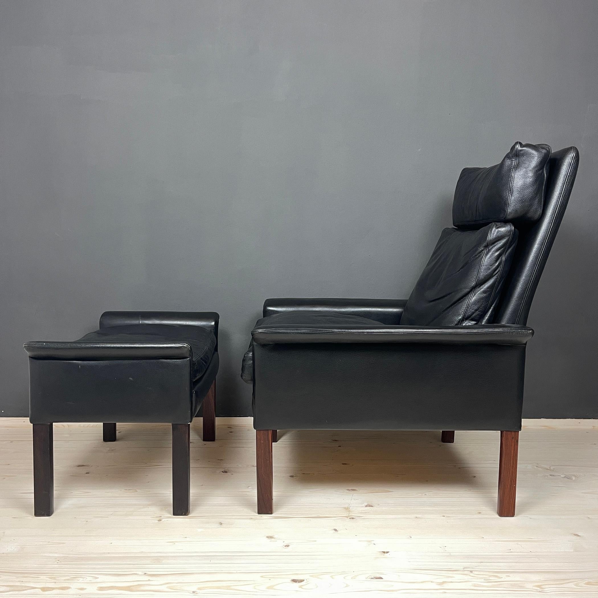 Hans Olsen's model 500 lounge chair and ottoman, which were created in Denmark for Vatne Møbler, are exquisitely weathered in black leather and mahogany. Flared armrests, crisp lines, and a charming low profile posture define this contemporary