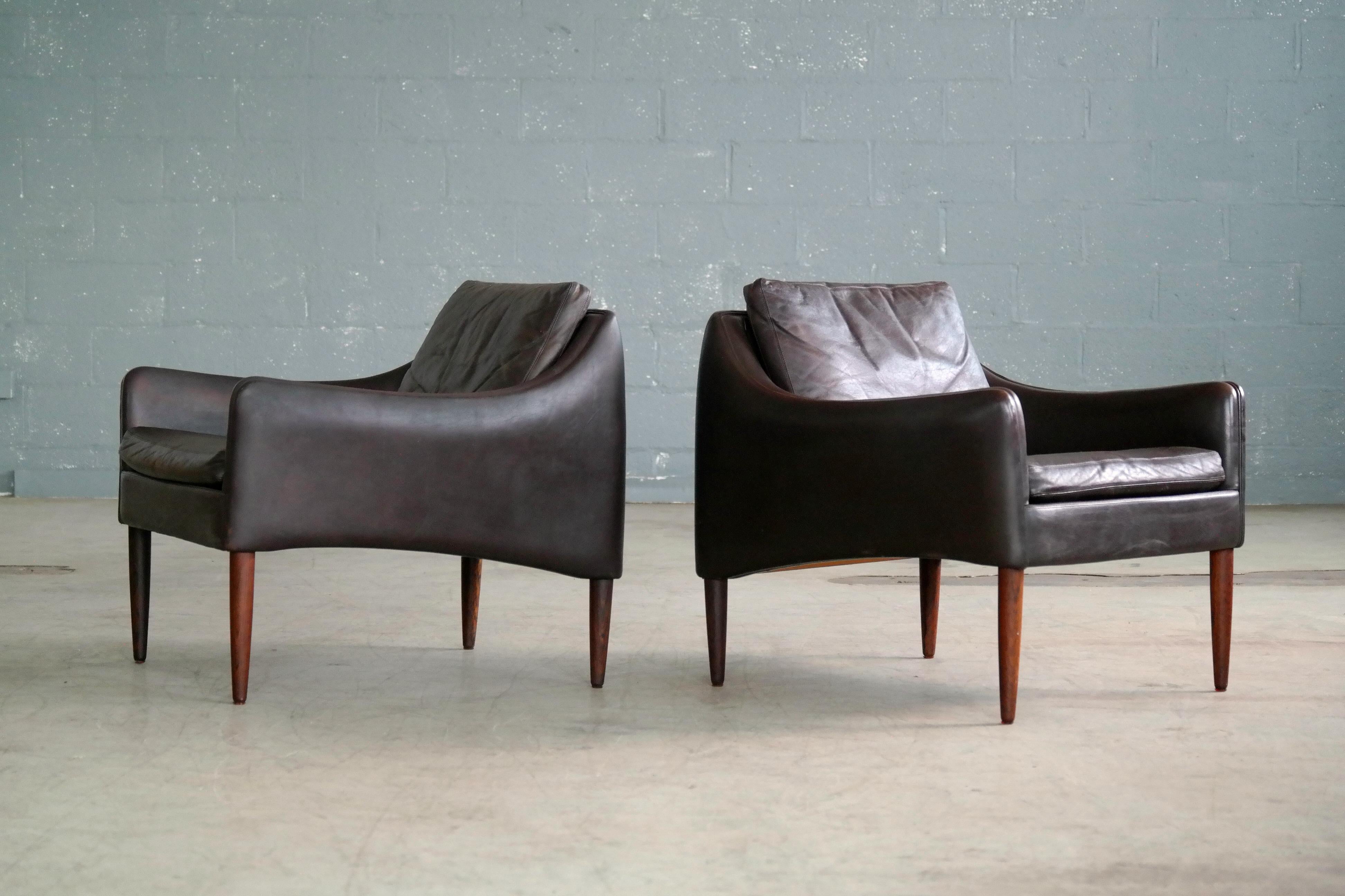 Stunning pair of lounge chairs designed by Hans Olsen in 1966 for CS Mobler of Glostrup right outside Copenhagen. The chairs are upholstered in a dark deep espresso colored leather raised on tall and slender tapered rosewood legs. The leather shows