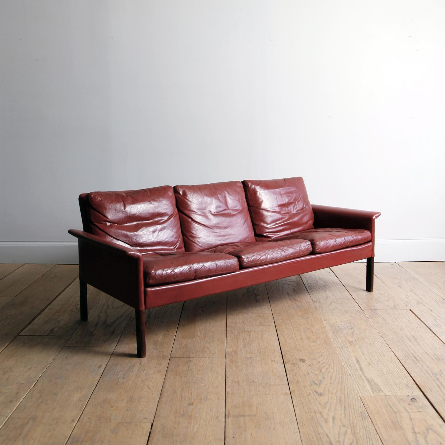 Hans Olsen was a cabinet-maker by training and later studied with the great architect-designer Kaare Klint. He prioritized comfort, and innovative use of materials.

This is a three-seat sofa with rosewood legs, wearing its original oxblood