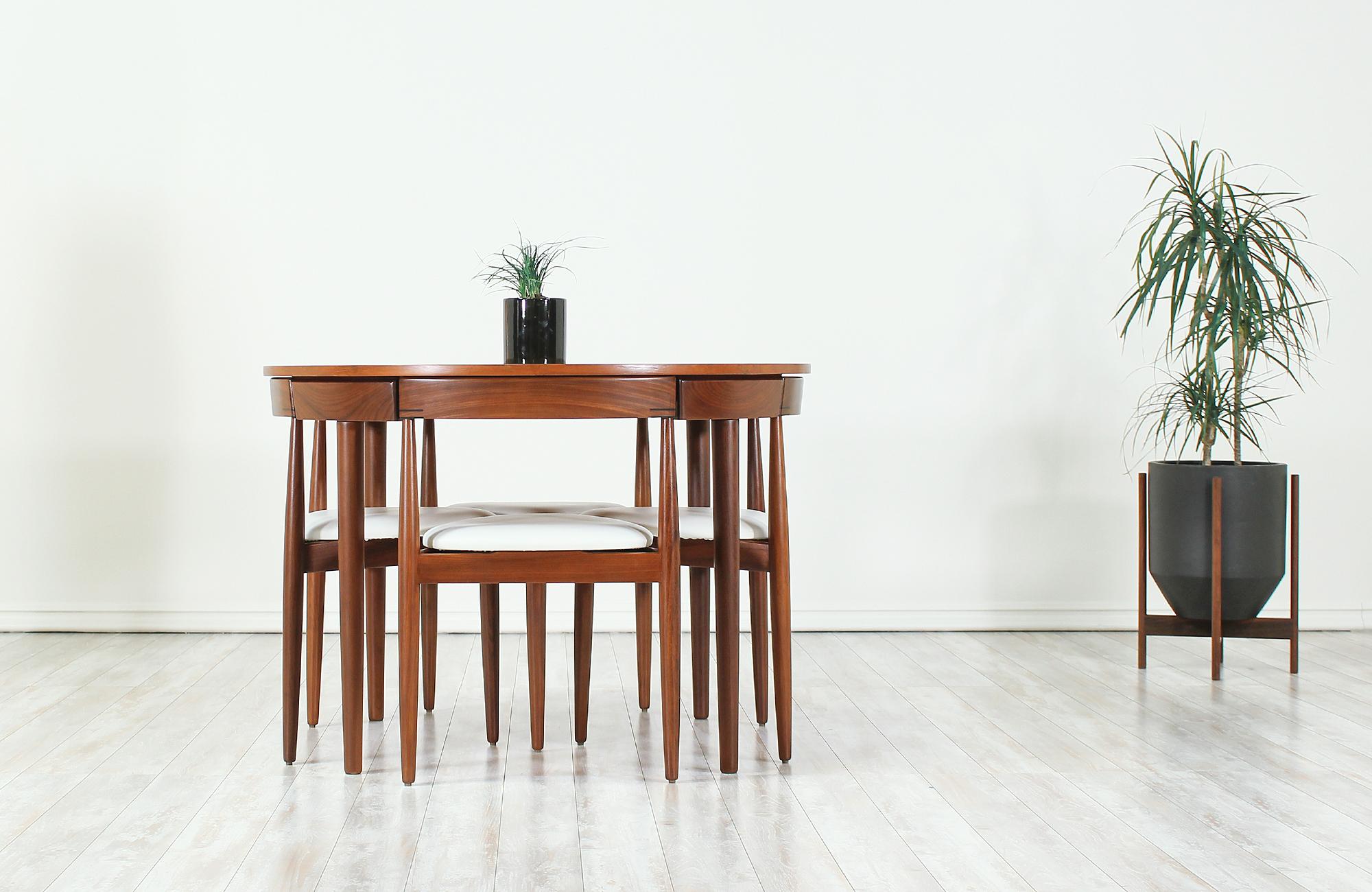 Unique “Roundette” dining set designed by Hans Olsen for Frem Rølje in Denmark, circa 1960s. This striking dining set features a teak wood round table and four dining chairs. The dining chairs seamlessly tuck into the table with their curved back