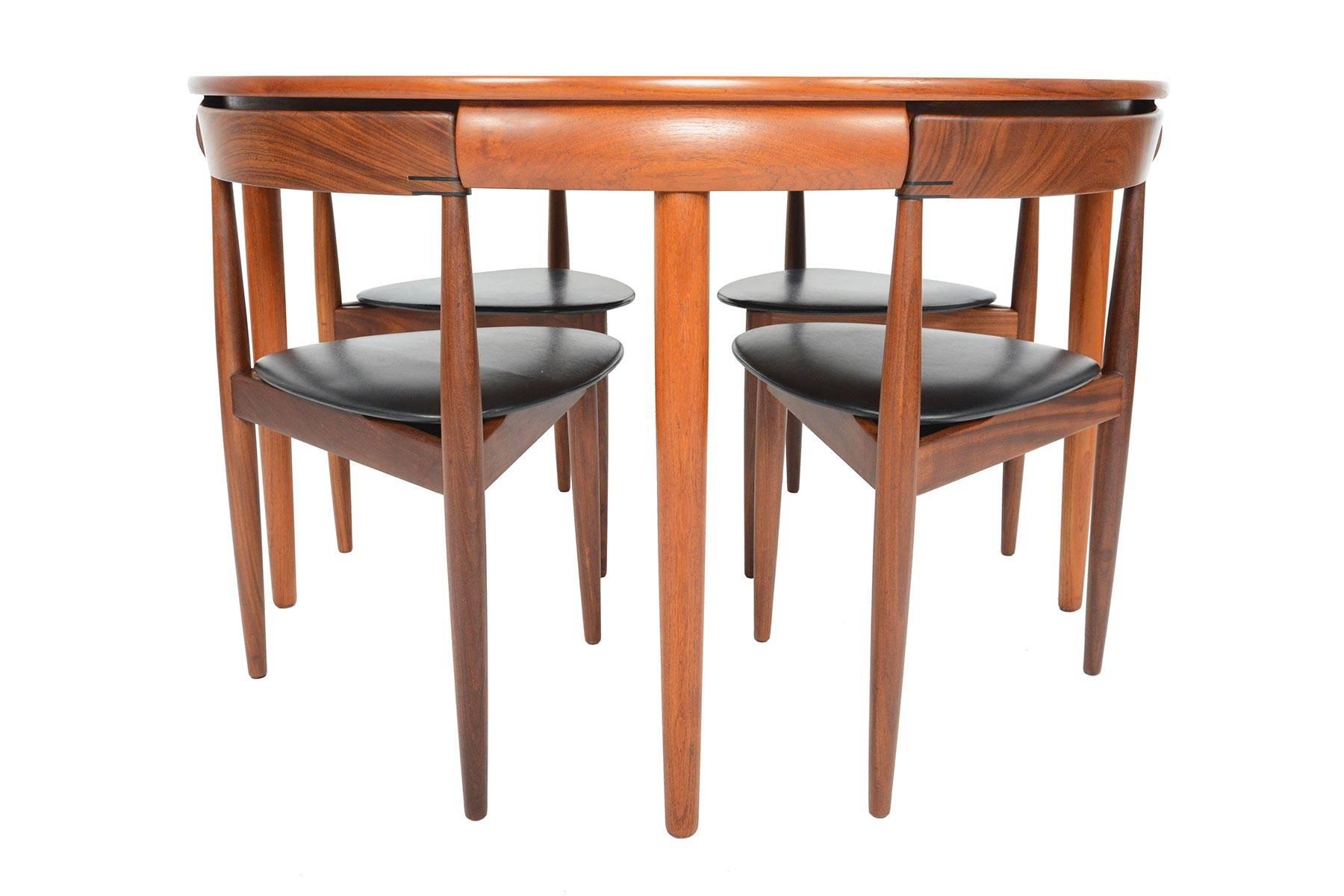 This highly sought after Danish modern “Roundette” dining set was designed by Hans Olsen for Frem Røjle Møbelfrabrik in 1952. Crafted in teak, this set is uniquely designed to nest four chairs into the banding for a seamless look. The chairs feature