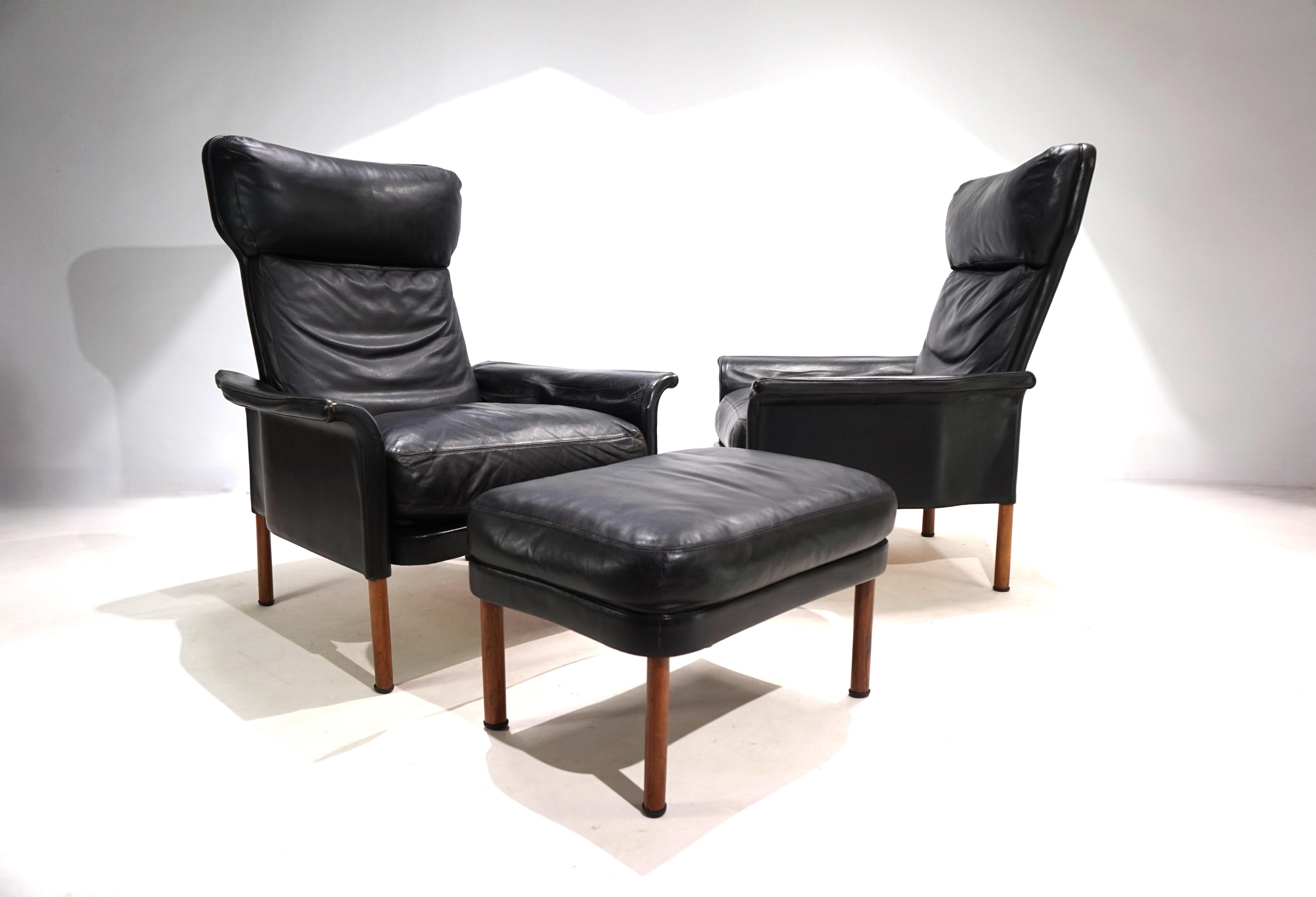 The two leather armchairs in black leather are in very good condition. The leather of the armchair and the ottoman is soft and has a light patina. The impressive design of the armchair is characterized by the curved shape of the base and the
