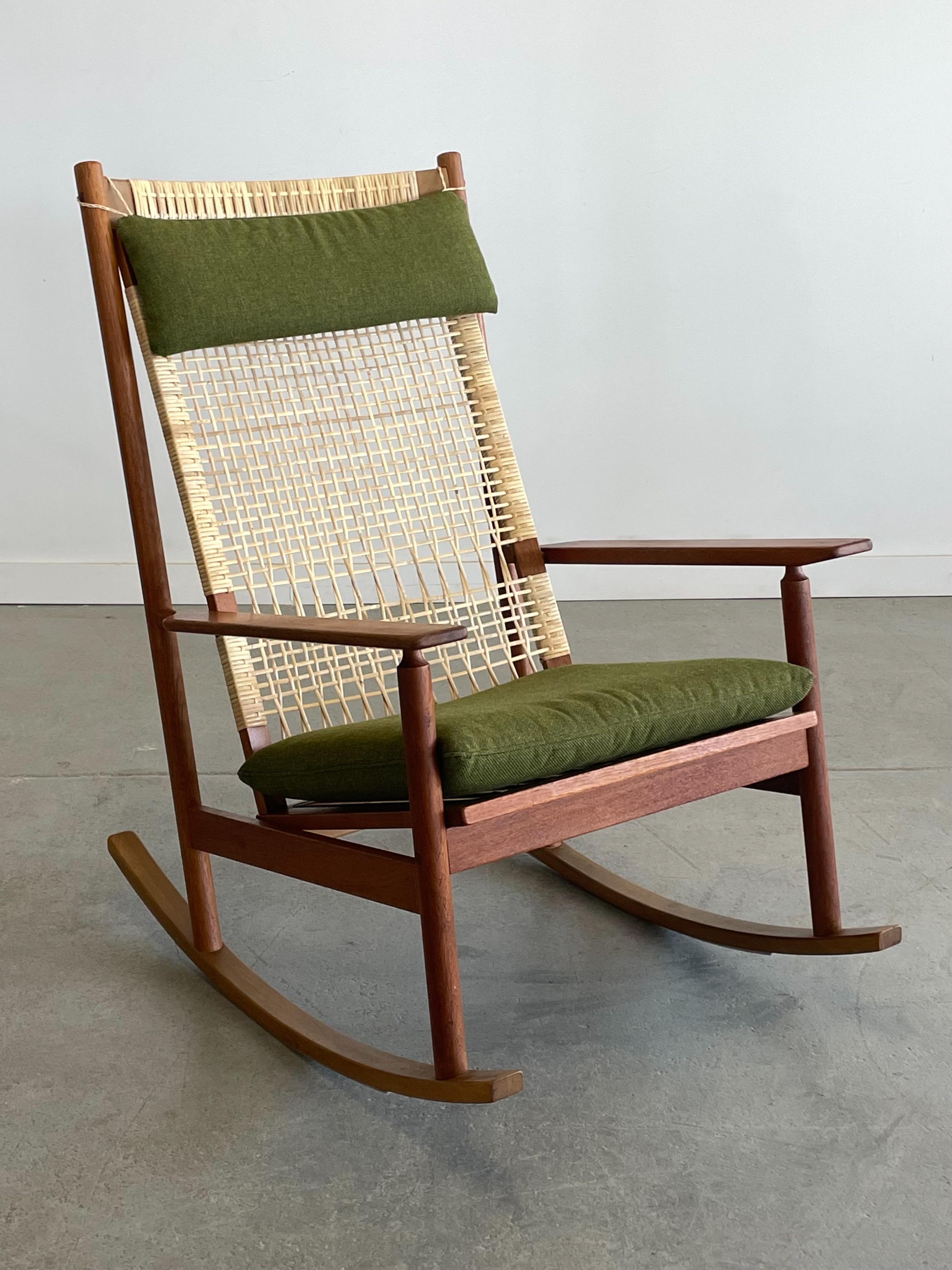 Stunning Model 532A teak and cane rocking chair designed by Hans Olsen for Juul Kristiansen, Denmark. This beautiful piece features an intricately woven backrest, sculpted arms, and original fabric. A statement piece in any environment. Measures 26”