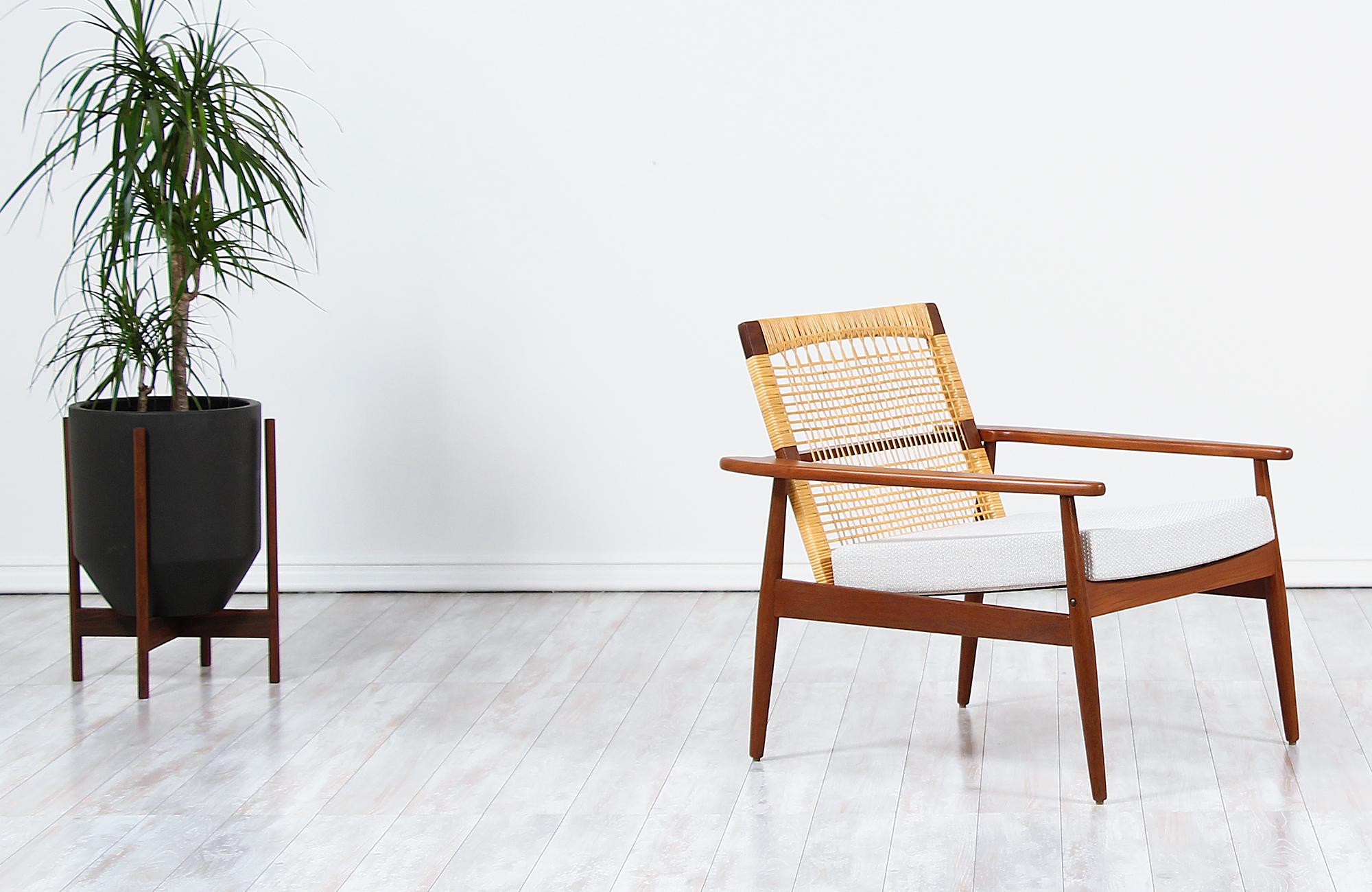 Danish modern lounge chair designed by Hans Olsen for Juul Kristensen in Denmark circa 1960s. This iconic chair by Hans Olsen is constructed from solid Afromosia teak wood that is found only in Africa, a newly Danish woven caned backrest and new