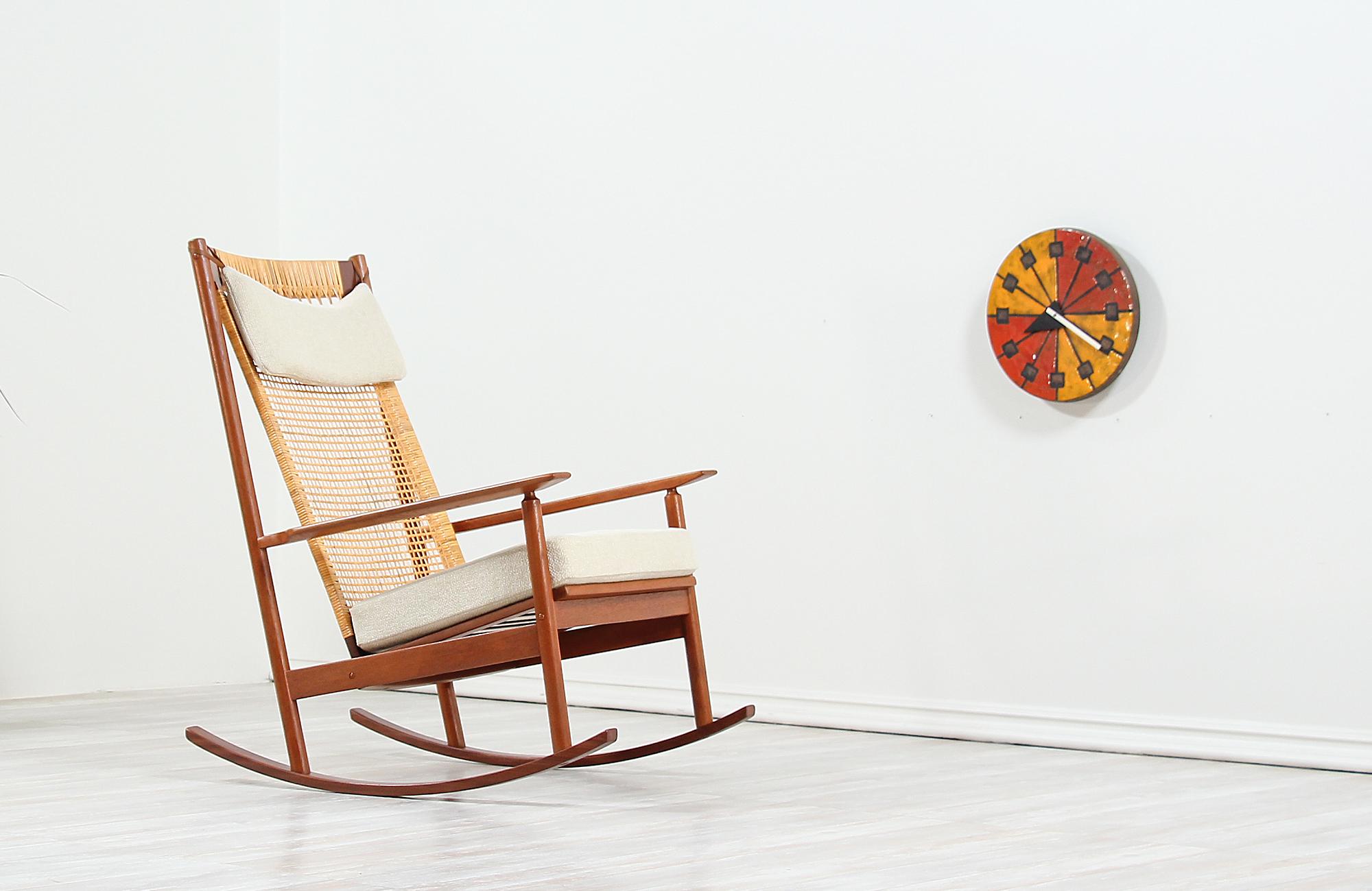 Stunning modern rocking chair designed by Hans Olsen for Juul Kristensen in Denmark, circa 1960s. This iconic Danish modern rocker design is crafted in solid teak wood featuring new hand weaved cane backrest and springs for sturdy support. The
