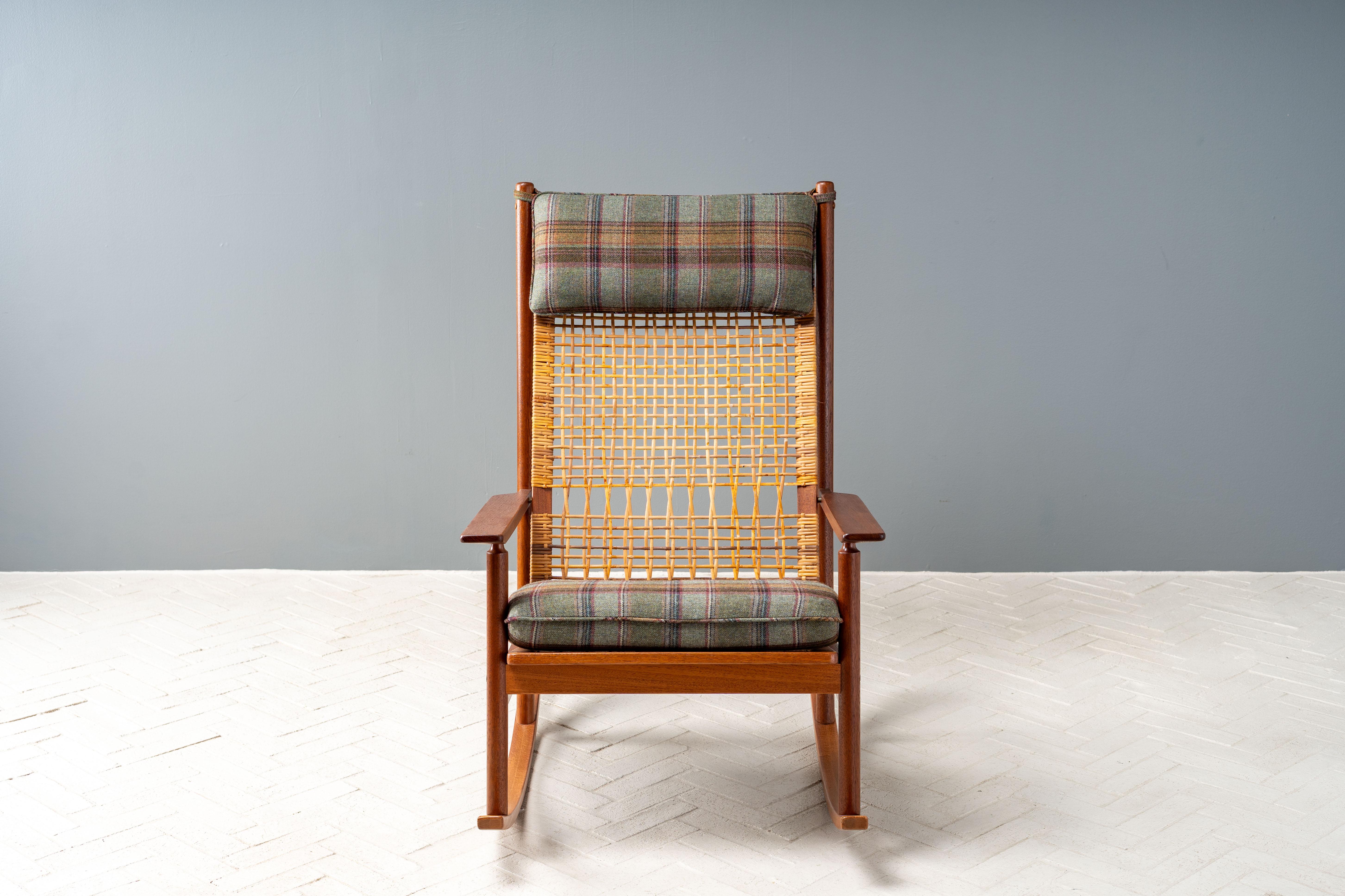Dinamarca, hacia la década de 1950. Una elegante mecedora de Hans Olsen para Juul Kristensen. Presenta una sólida estructura de teca con brazos rectos biselados y respaldo alto de caña. El cojín reversible del asiento y el reposacabezas se han