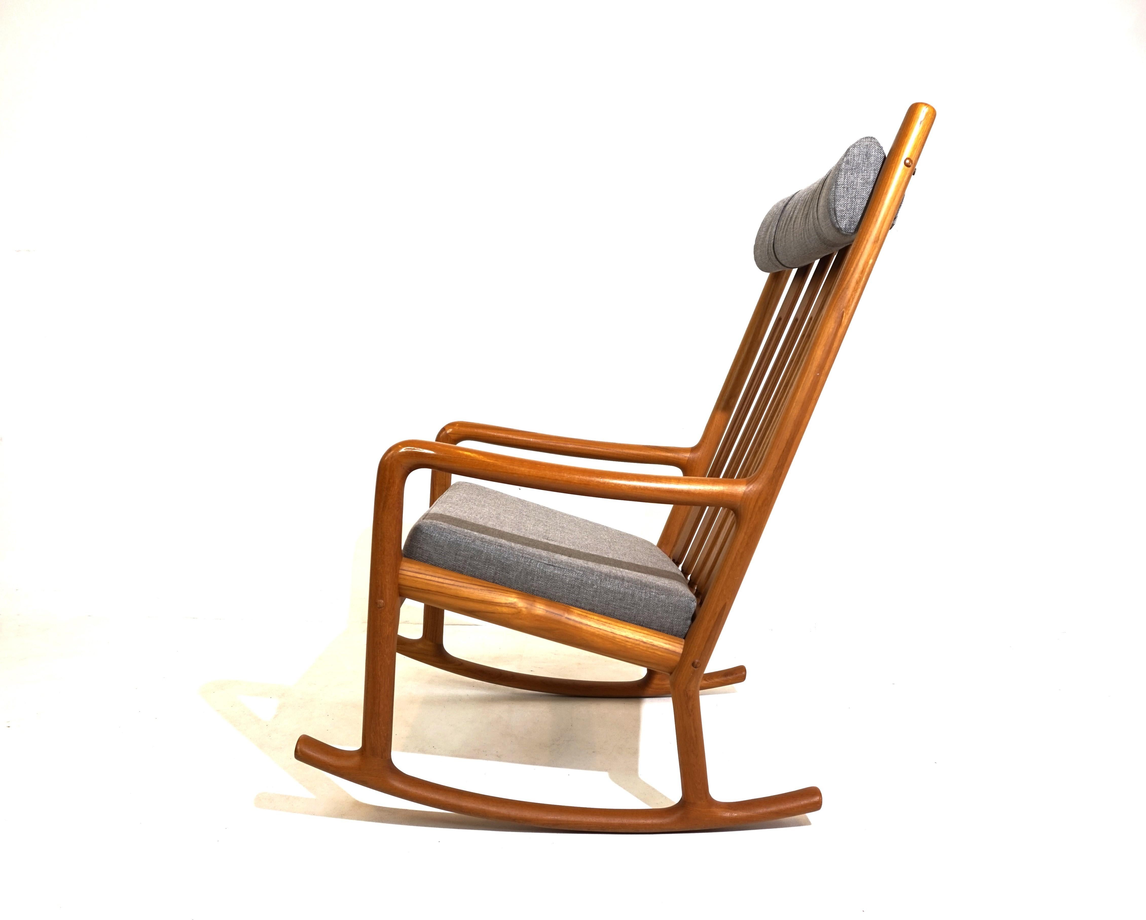 The rocking chair with a solid teak frame and delicate inserts in the backrest comes in very good condition. The wooden frame shows only minimal signs of wear and has a very attractive warm wood tone. The seat cushion and neck cushion have been