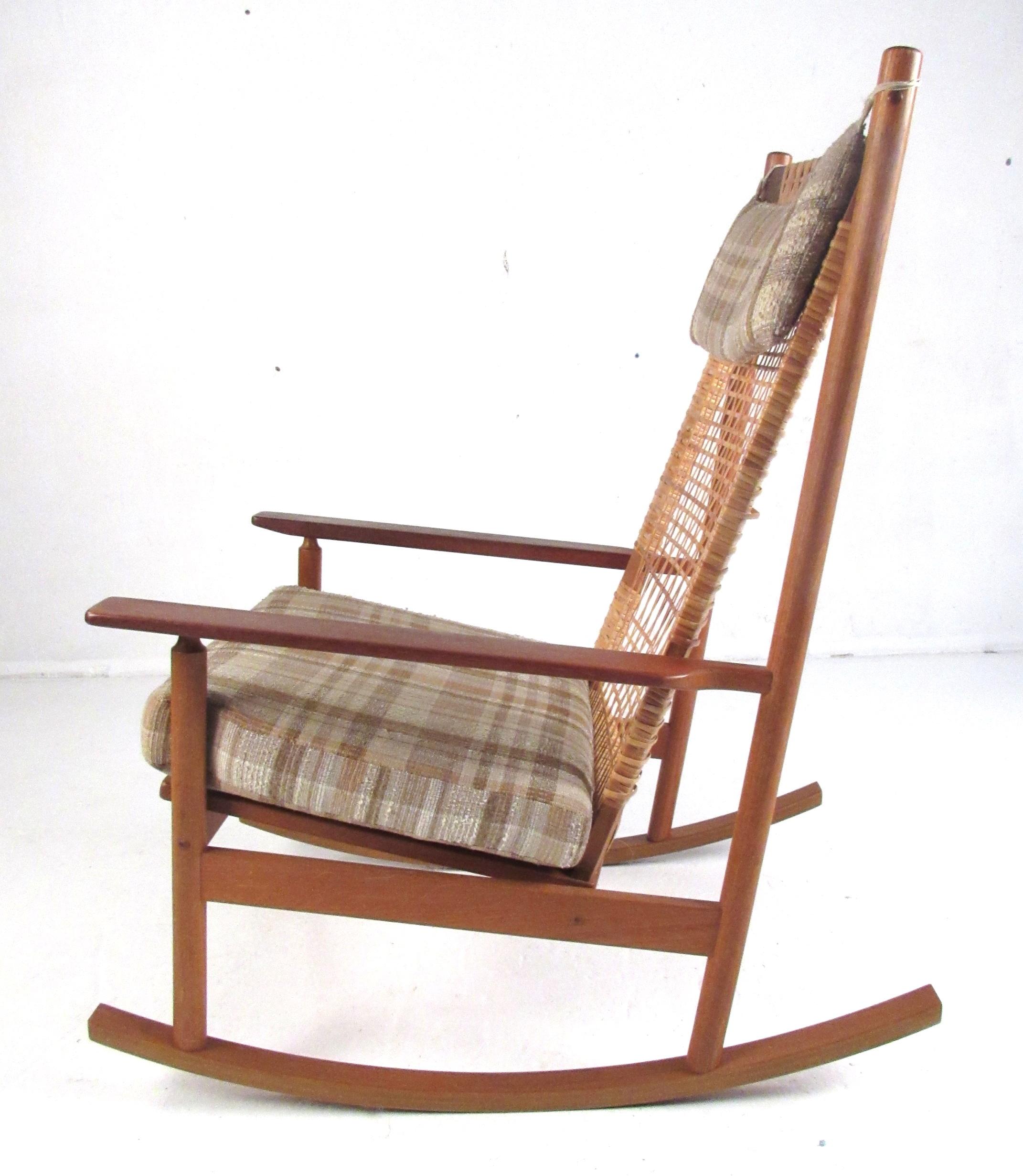 This beautiful Danish modern teak rocking chair was designed by Hans Olsen and produced by Juul Kristensen, circa 1963. It features a wonderful woven cane back complimented by thin edge tapered armrests with an upholstered seat and headrest. Stamped
