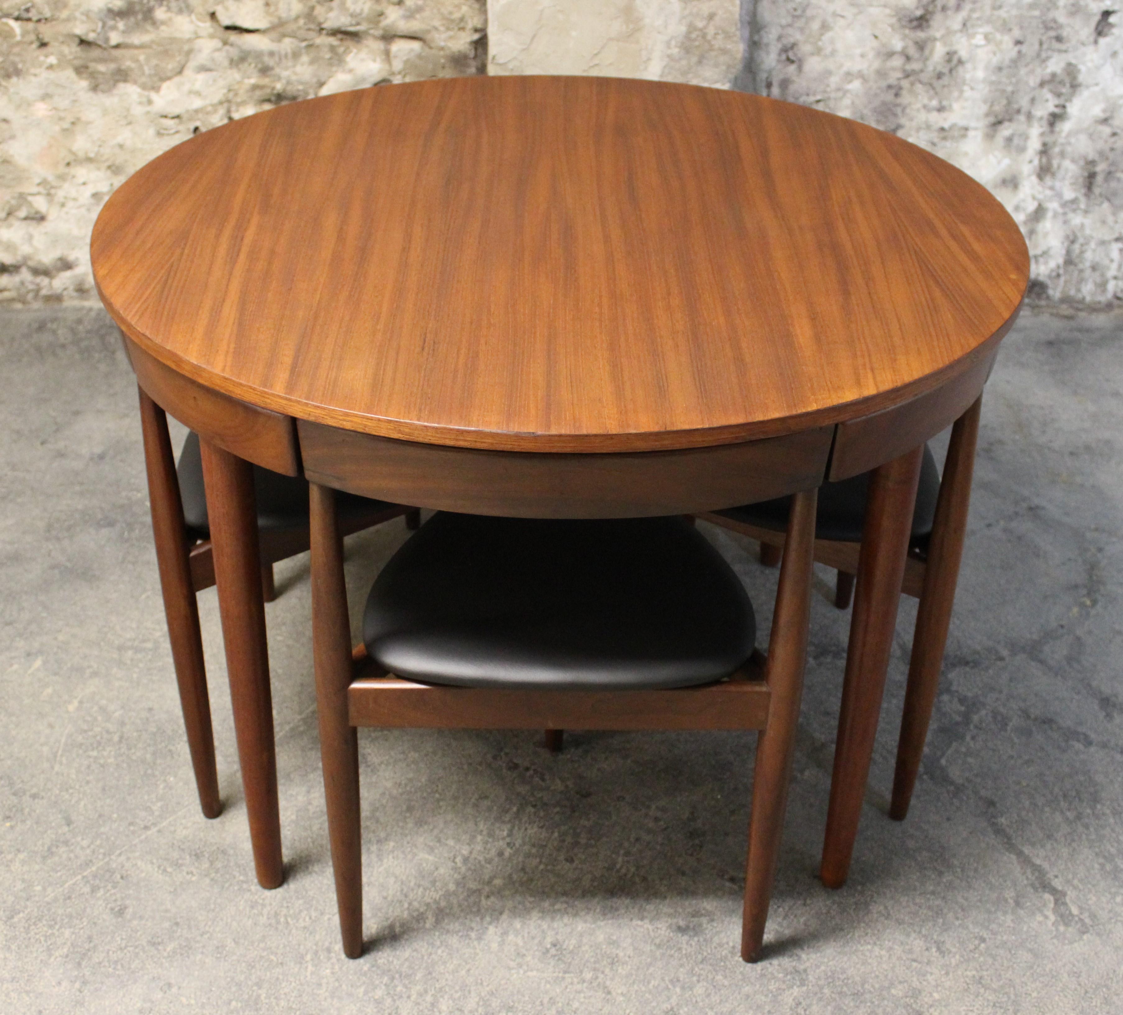 This teak Roundette model dining set, consisting of one dining table and four chairs was designed by Hans Olsen, and manufactured by Frem Rojle. The striking three-legged chairs fit smoothly under the table saving on space while giving a clean,
