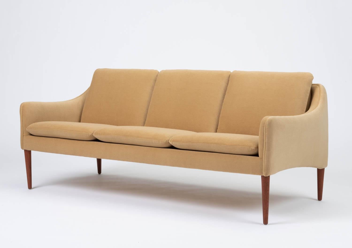Minimalist three seat sofa by Danish designer Hans Olsen for CS Møbler, circa 1960. The sculpted frame has been newly recovered in a sophisticated camel colored Italian 100% mohair and the straps have been replaced with new webbing. The tapered teak