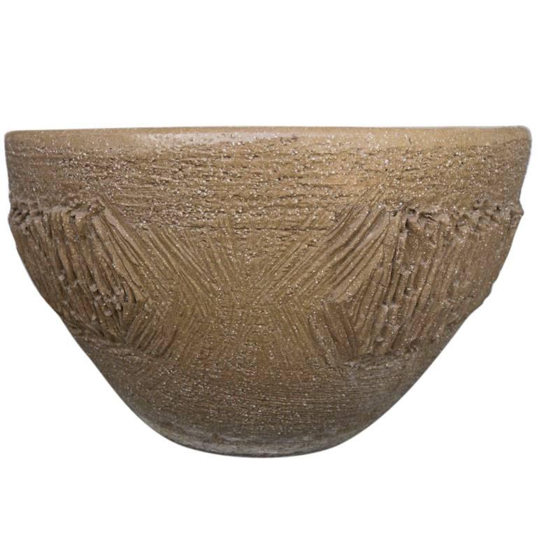 This planter has a coarse texture above and below the decorative vertical clay scrape design around the mid section.

 