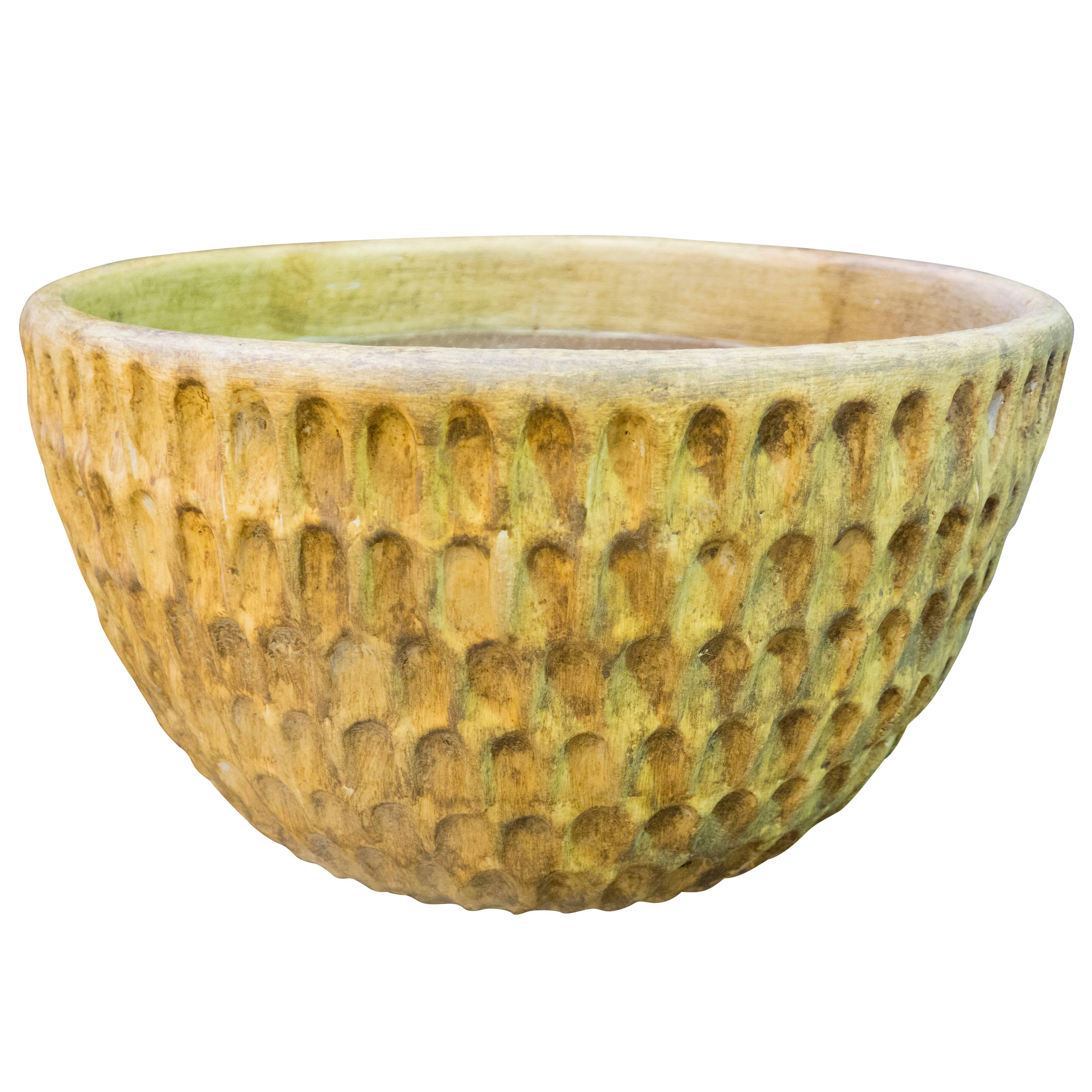The thumb pot is from a collaboration of Hans Stumpf and Stan BItters and is known for its thumb sized dimples and thick heavy aesthetic. This molded planter was created circa 1980 and has a ochre finish. This is a lovely piece of American garden