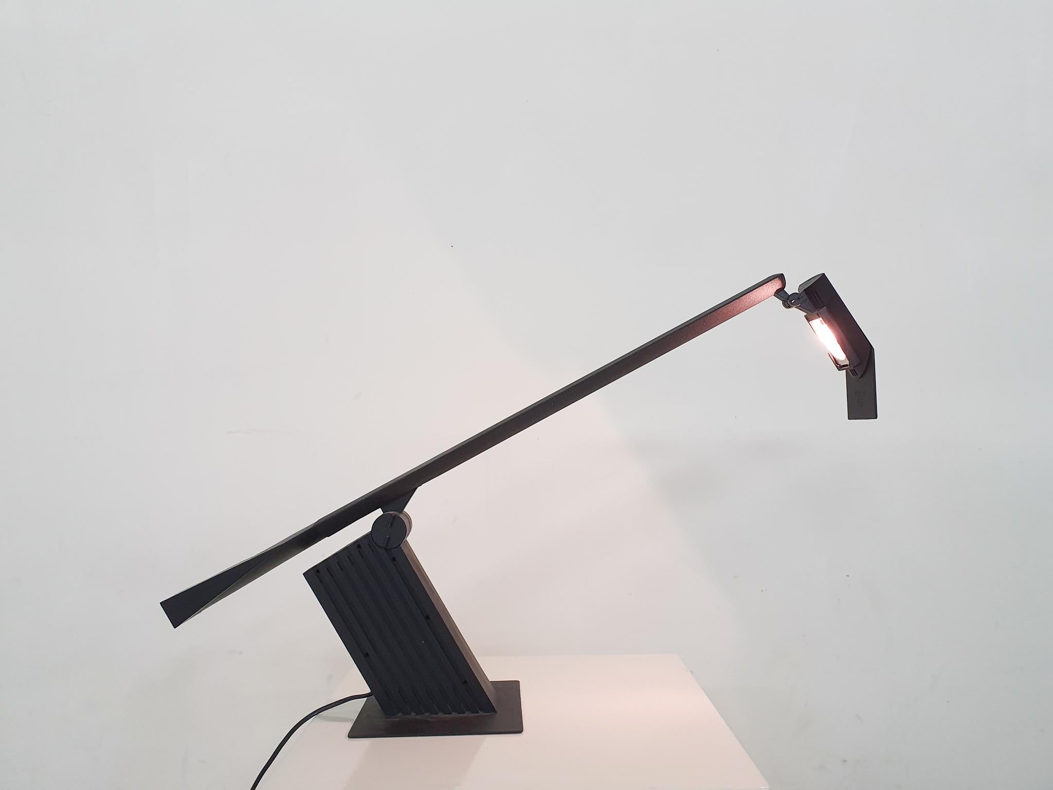 Verstellbare Schreibtischleuchte aus schwarzem Kunststoff und Metall, entworfen von Hans von Klier für Bilumen.
Die Leuchte verwendet eine Halogenlampe. Auf dem Kopf, neben der Halogenlampe, befindet sich ein Chip aus Kunststoff.