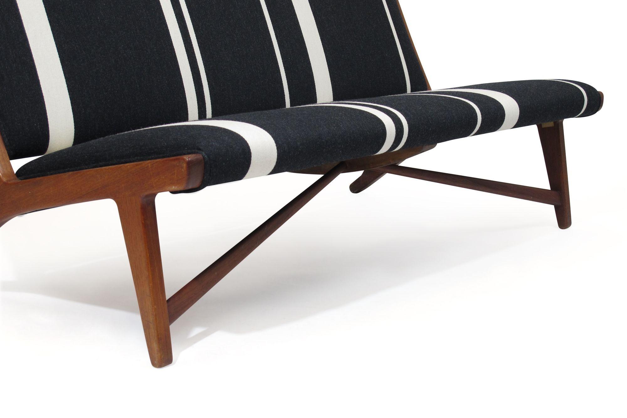 Danish armless bench designed by Hans Wegner. Model JH555, crafted of a solid teak frame with angled cross stretcher. Newly upholstered in classic Scandinavian striped wool textile by Tove and Edvard Klint Larsen.
 
This bench was designed by Hans