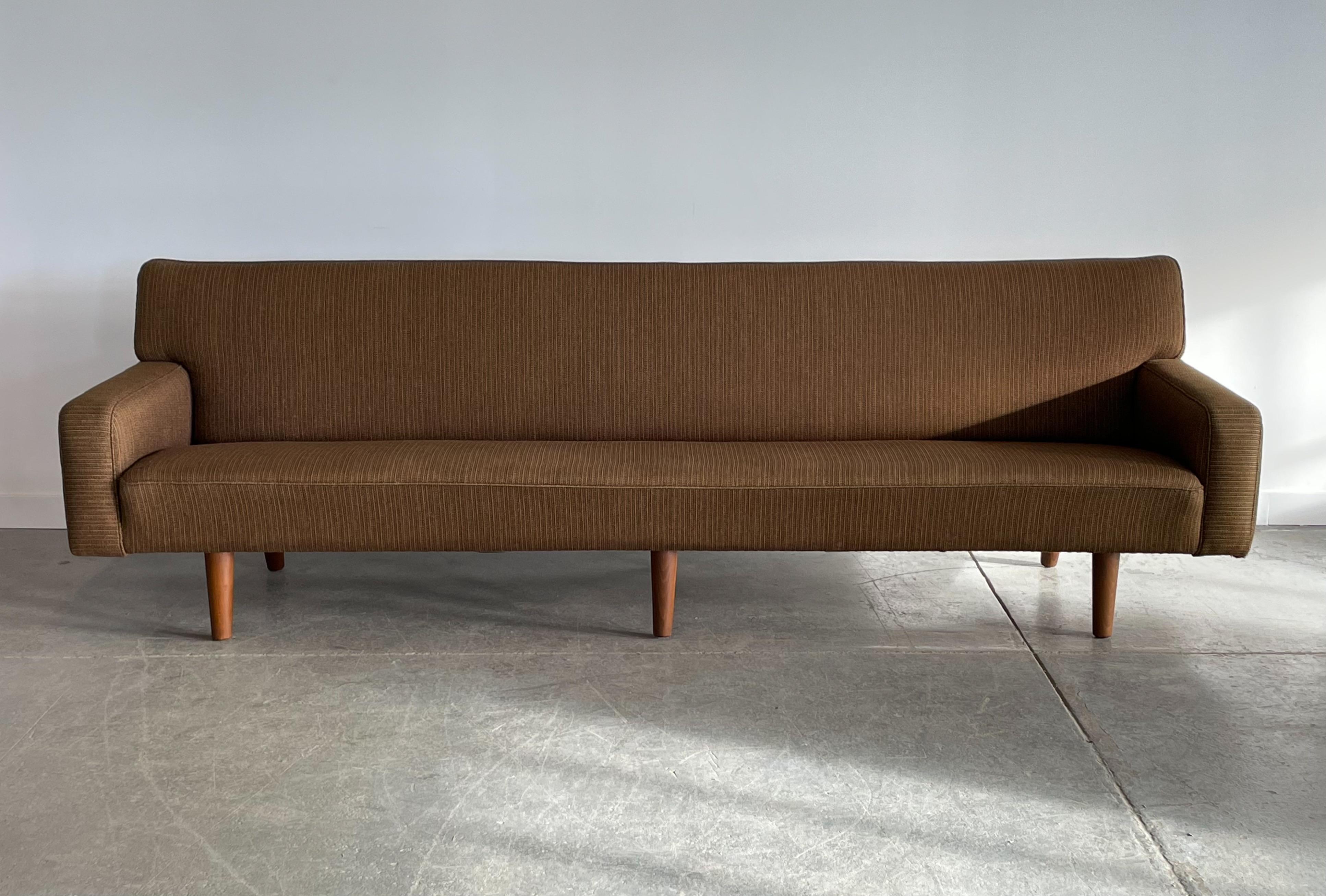 Monumental and rare four-seater AP33 sofa designed by Hans Wegner for AP Stolen, Denmark. This piece features angled oak legs and the original wool upholstery. It has a streamlined and almost contemporary silhouette, which would make it at home in a