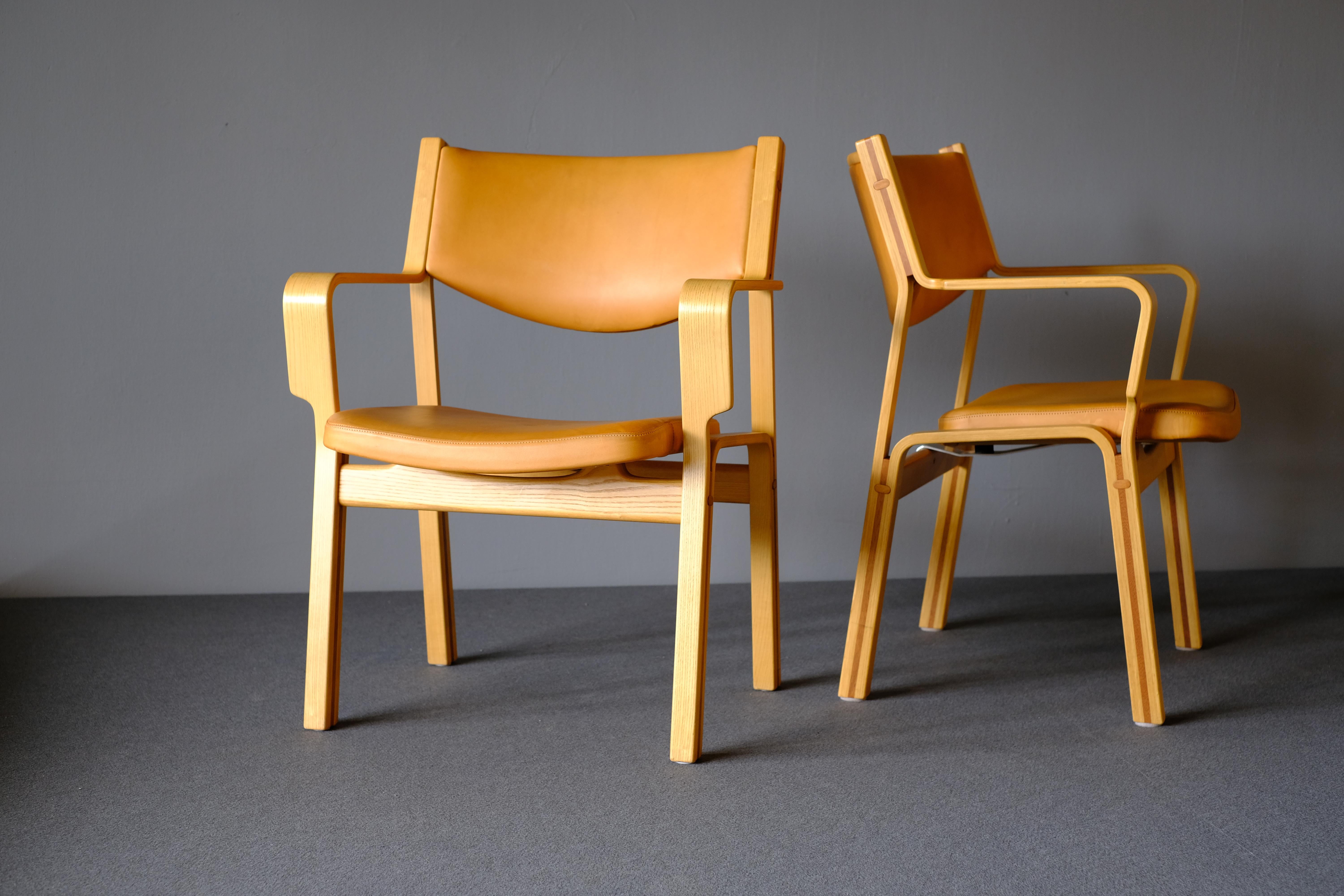 Pair of matching armchairs JH 47-2, designed by Hans Wegner in 1979 for Johannes Hansen. These chairs are in ash with mahogany inlays. The seat and back are upholstered with patinated natural leather which will continue to deepen in color over time.