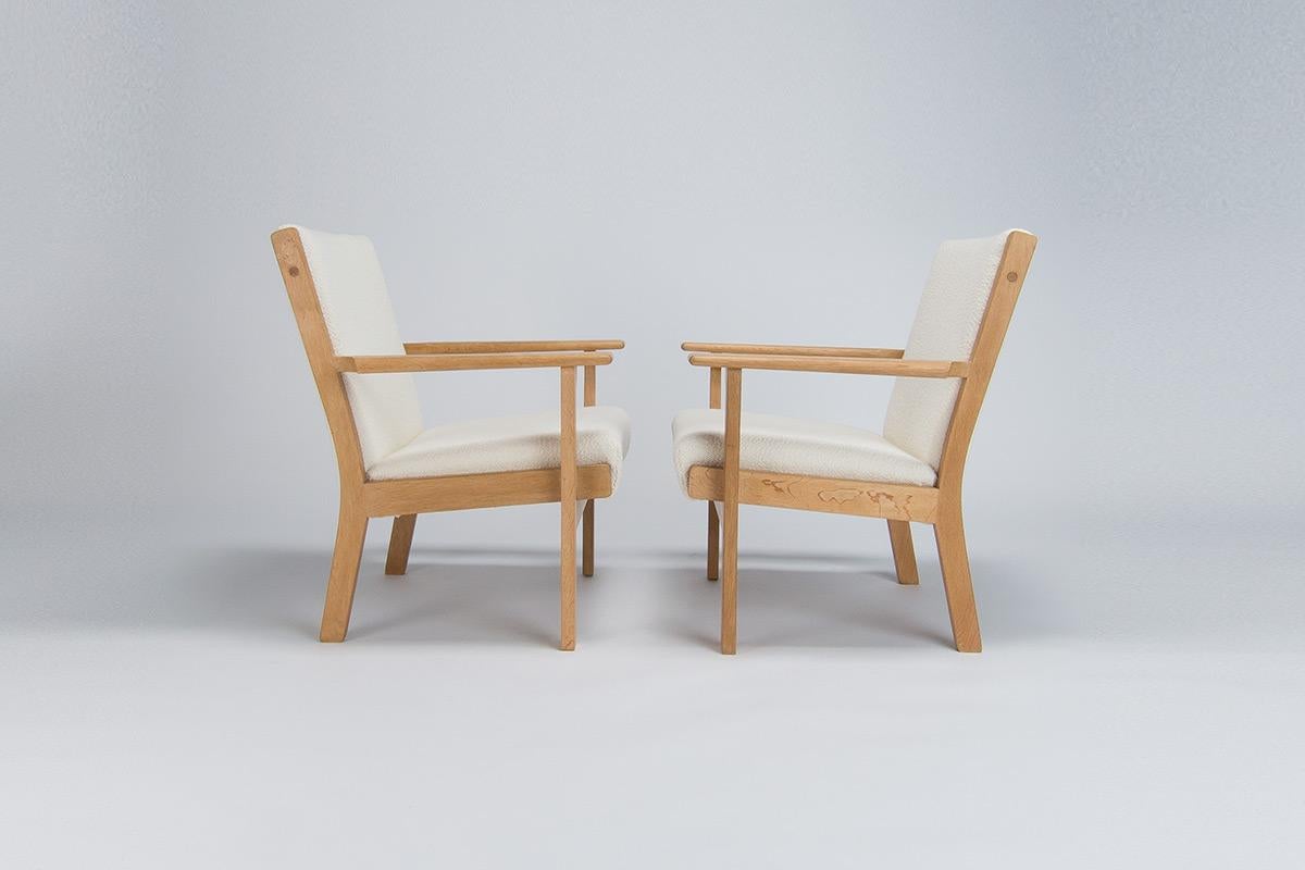 An attractive pair of Hans Wegner armchairs in oak made by Getema in the 1960’s. A simple and elegant design by one of the preeminent designers of the period Hans Wegner these chairs have been newly finished in a traditional Danish soap finish which