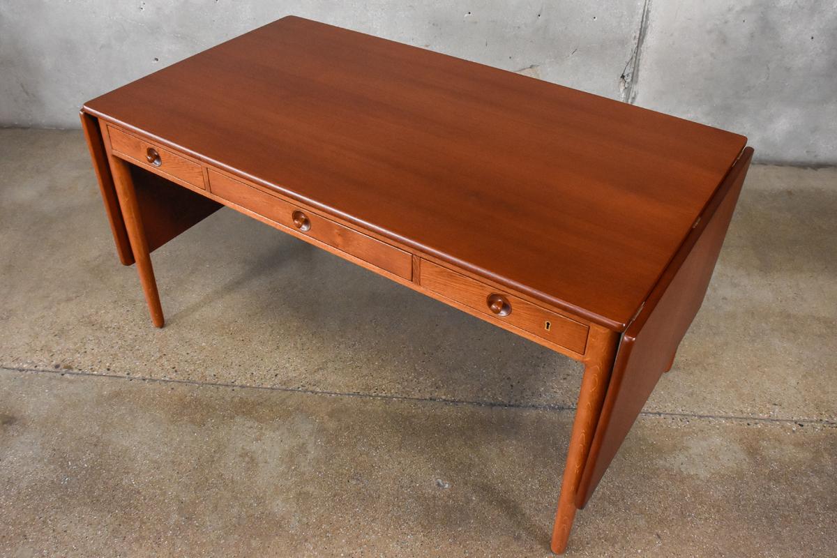 A teak and oak drop leaf desk designed by Hans Wegner for Andreas Tuck in 1955, model AT-305. This example has a teak top and oak legs. It has been completely restored and is in excellent condition. Retains the manufactures stamp on the