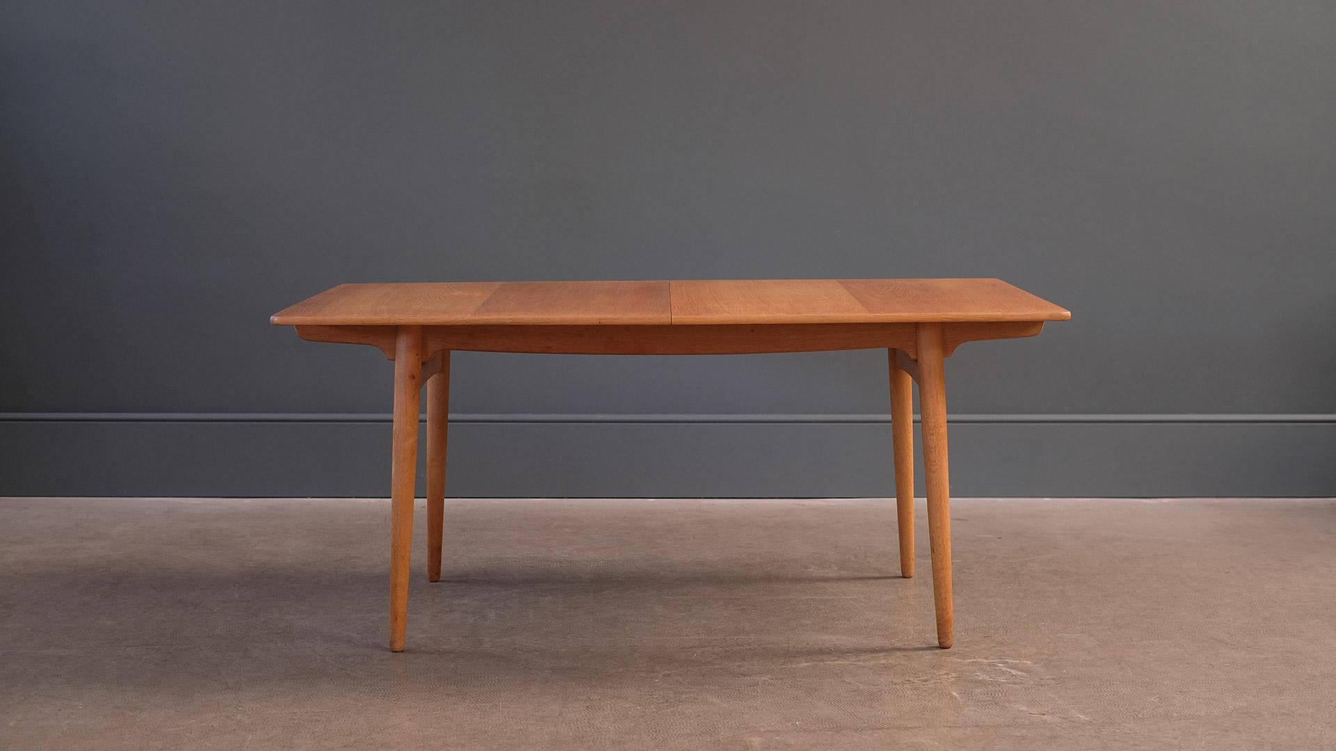 Fantastic extending dining table designed by Hans Wegner model AT 310 for Andreas Tuck, Denmark. This example in beautifully figured oak with two internally stowed leaves. Very elegant proportions and beautiful detailing.