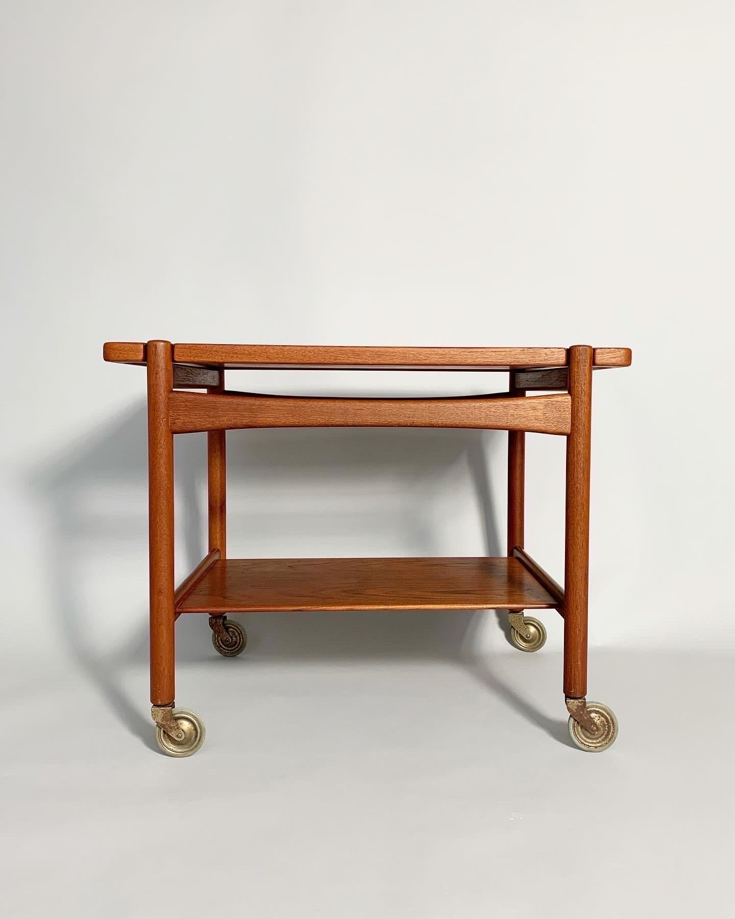 Hans Wegner bar cart, model AT-48 for Andreas Tuck in Denmark, 1950s.

Fully constructed of solid teak wood, even the reversible top, which can be used as a tray.

The wood was cleaned and refinished with oil. Original early wheels, partly worn