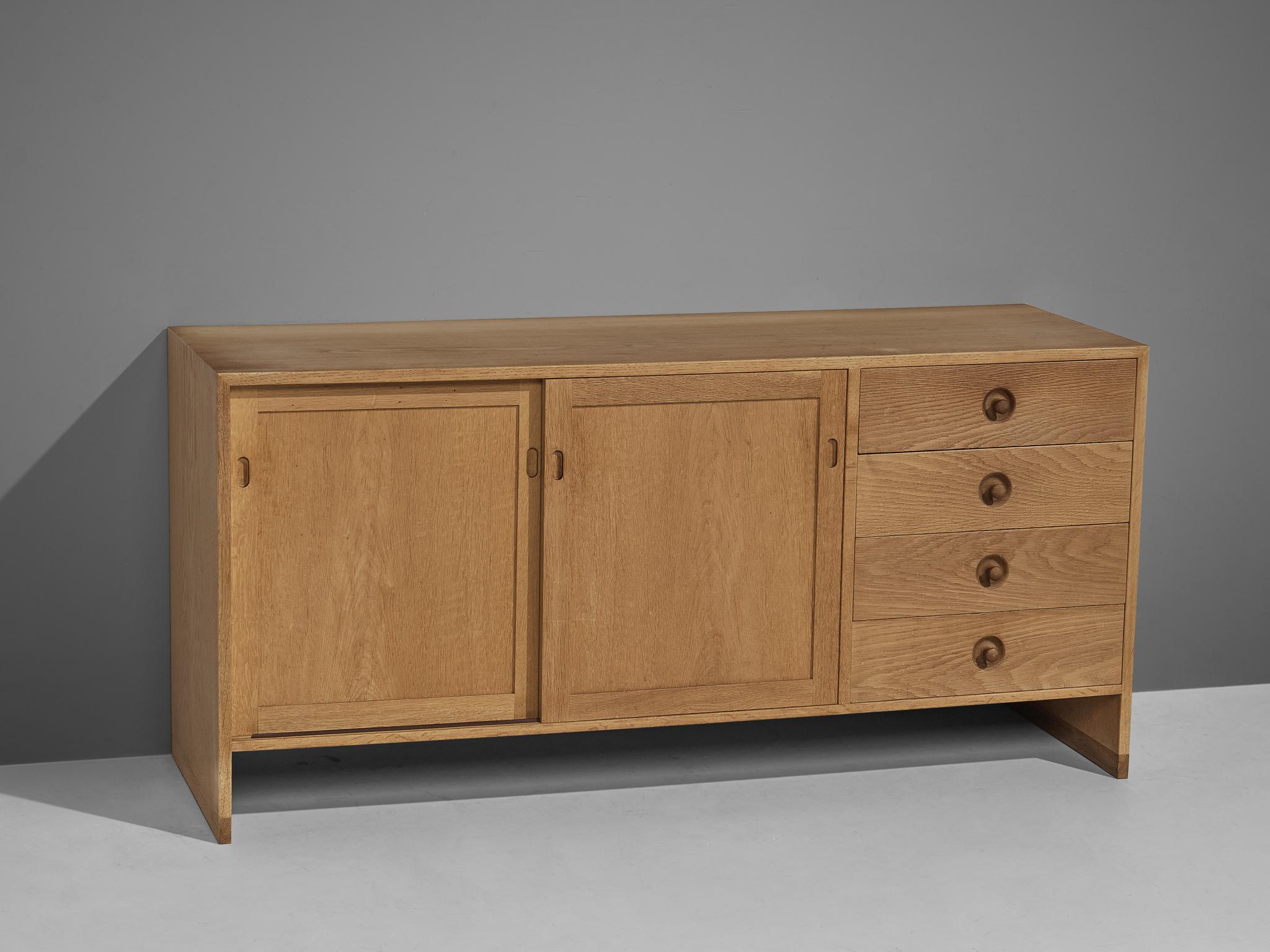 Hans Wegner for Ry Møbler, cabinet, oak, Denmark, 1960s.

This cabinet is executed in oak and is typical for midcentury Scandinavian design. It contains two sliding doors which reveals two inner compartments with shelves. On the right side, four