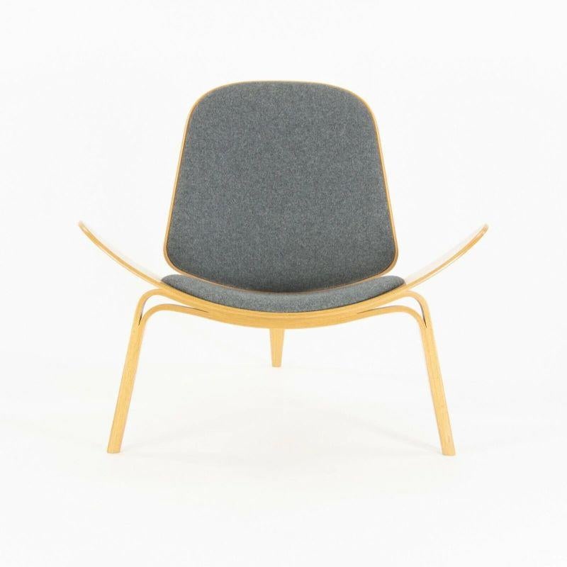 Listed for sale is a pair of (sold separately) CH07 shell chairs in lacquered oak with wool fabric seats, designed by Hans Wegner and crafted by Carl Hansen and Sons in Denmark.