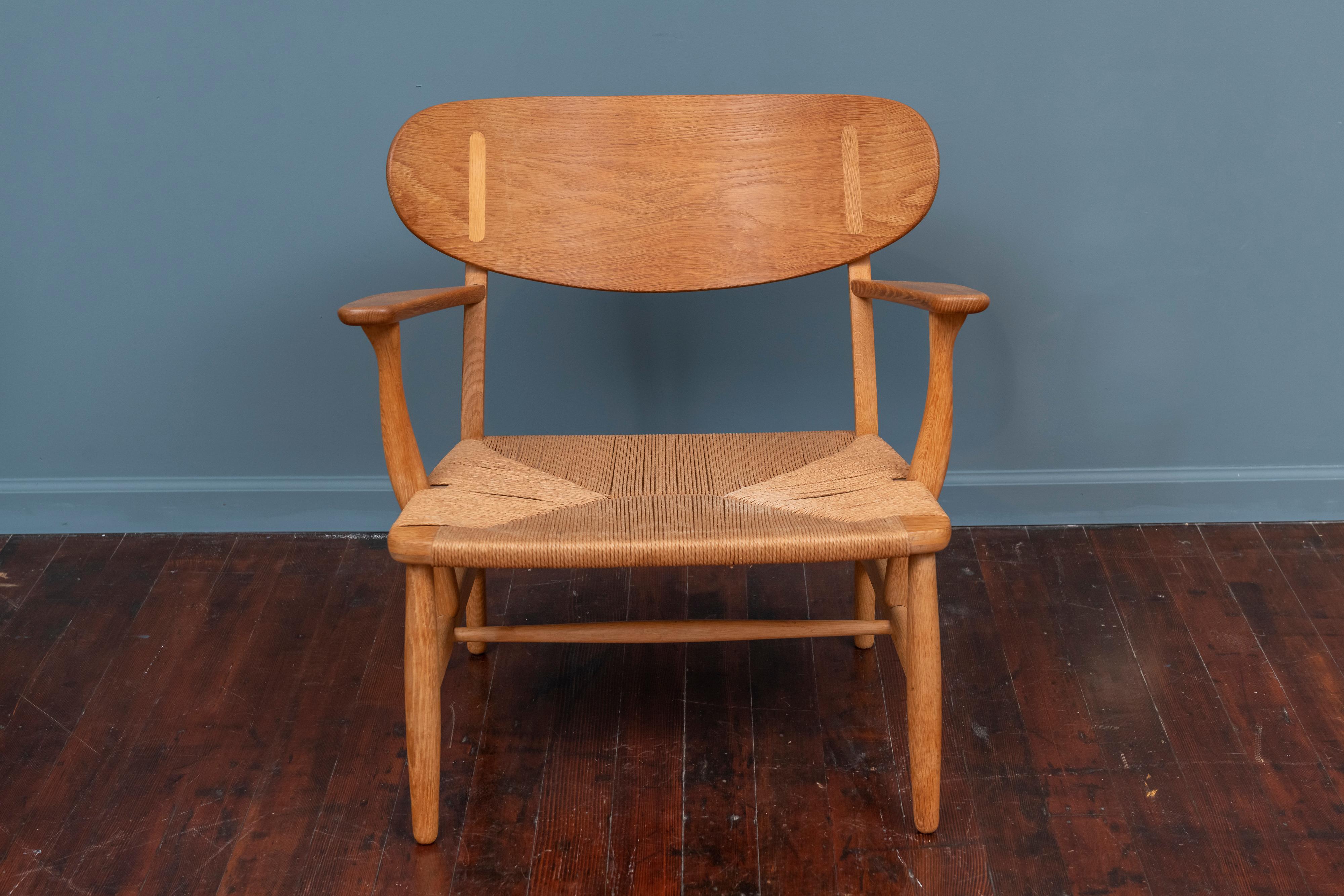 Hans Wegner CH-22 oak and teak lounge chair for Carl Hansen & Son, Denmark. Beautiful vintage production example fully stamped underneath the arm and in very good original condition. Organic, sculptural design that is timeless and comfortable.