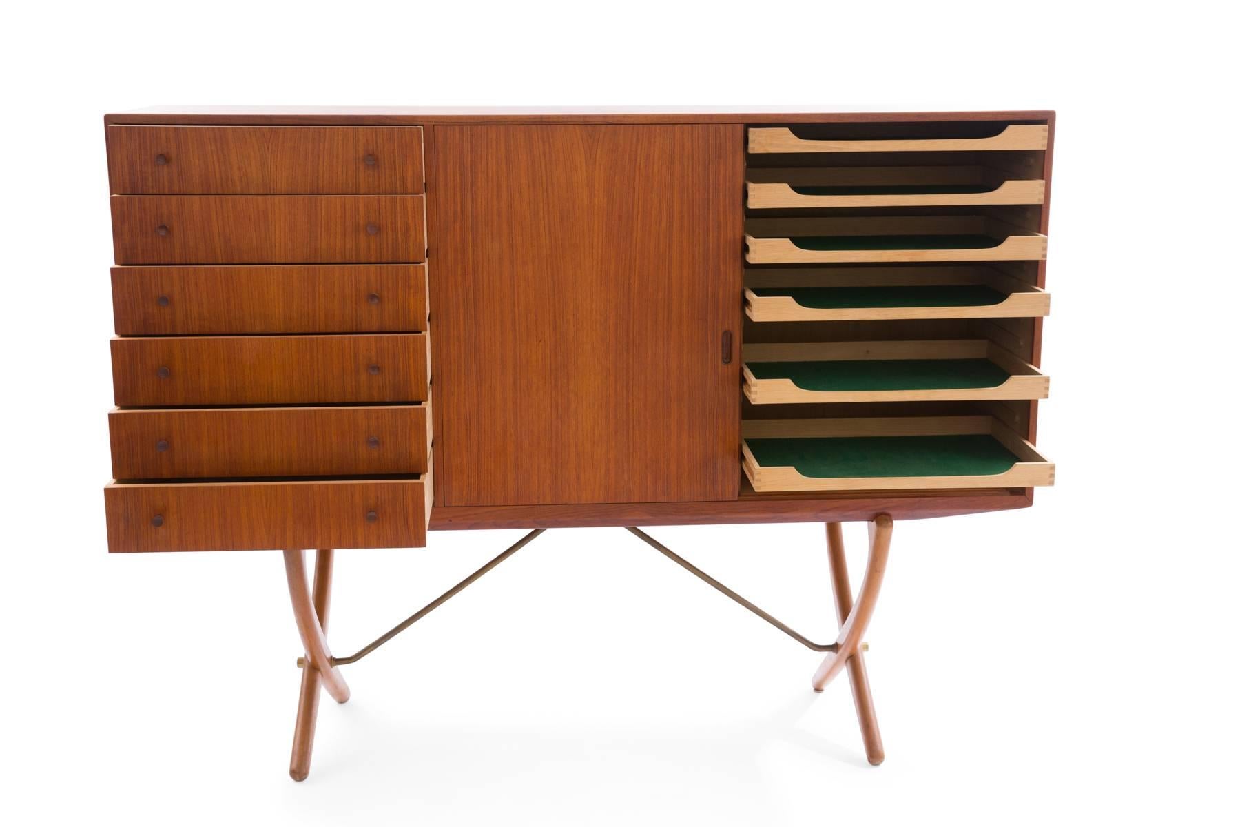 Hans Wegner for Carl Hansen CH-304 sideboard or credenza, circa late 1950s. This sculptural example has six exterior drawers with tapered solid teak pulls. There are two sliding doors with six pull-out drawers within and three adjustable shelves.