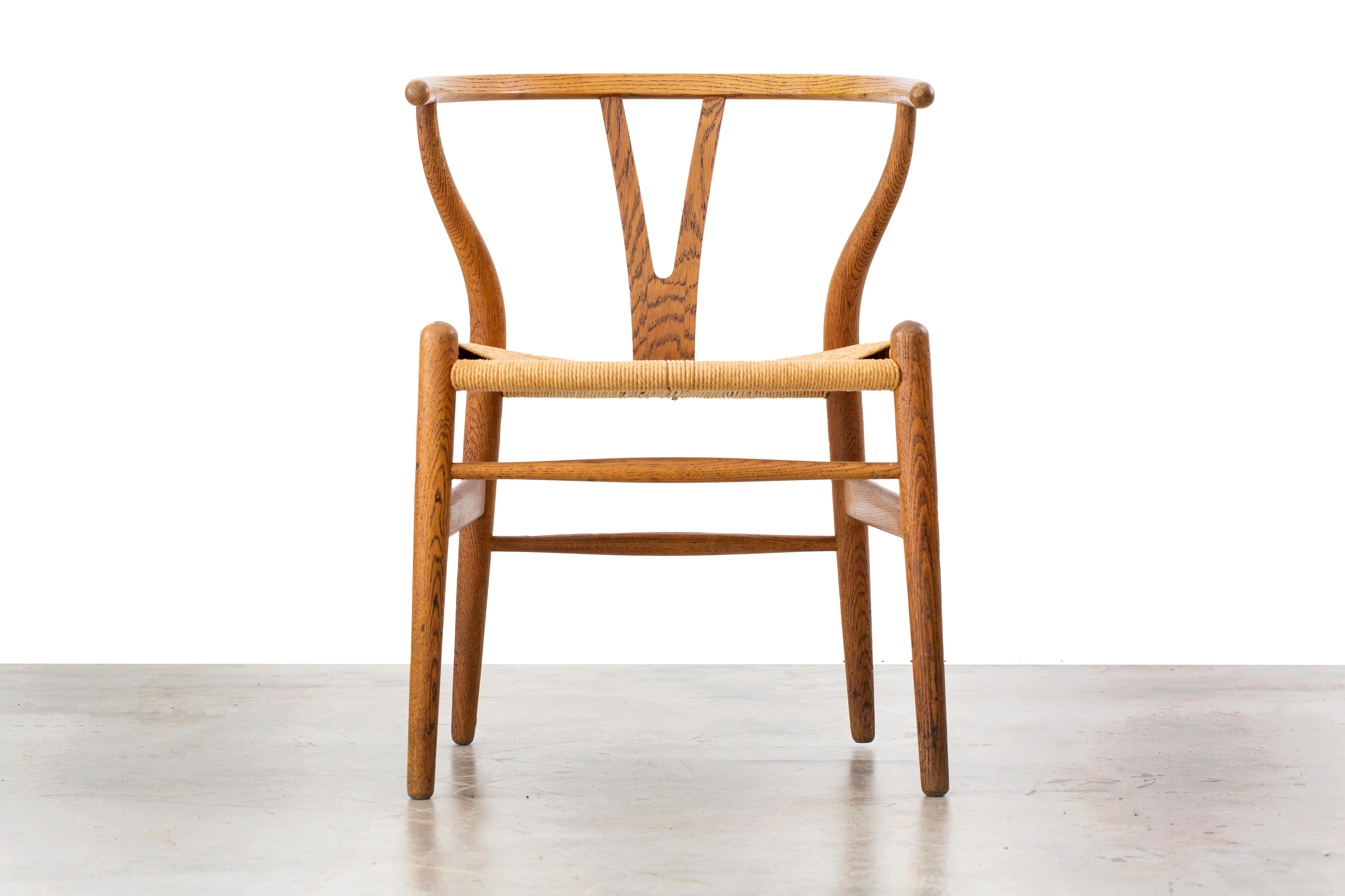 The Iconic wishbone chair, model number CH24, designed by Hans Wegner and imported by Illums Bolighus. This example is a time capsule piece, with original oak and paper cord seat all in fantastic condition. This chair would work well alongside works