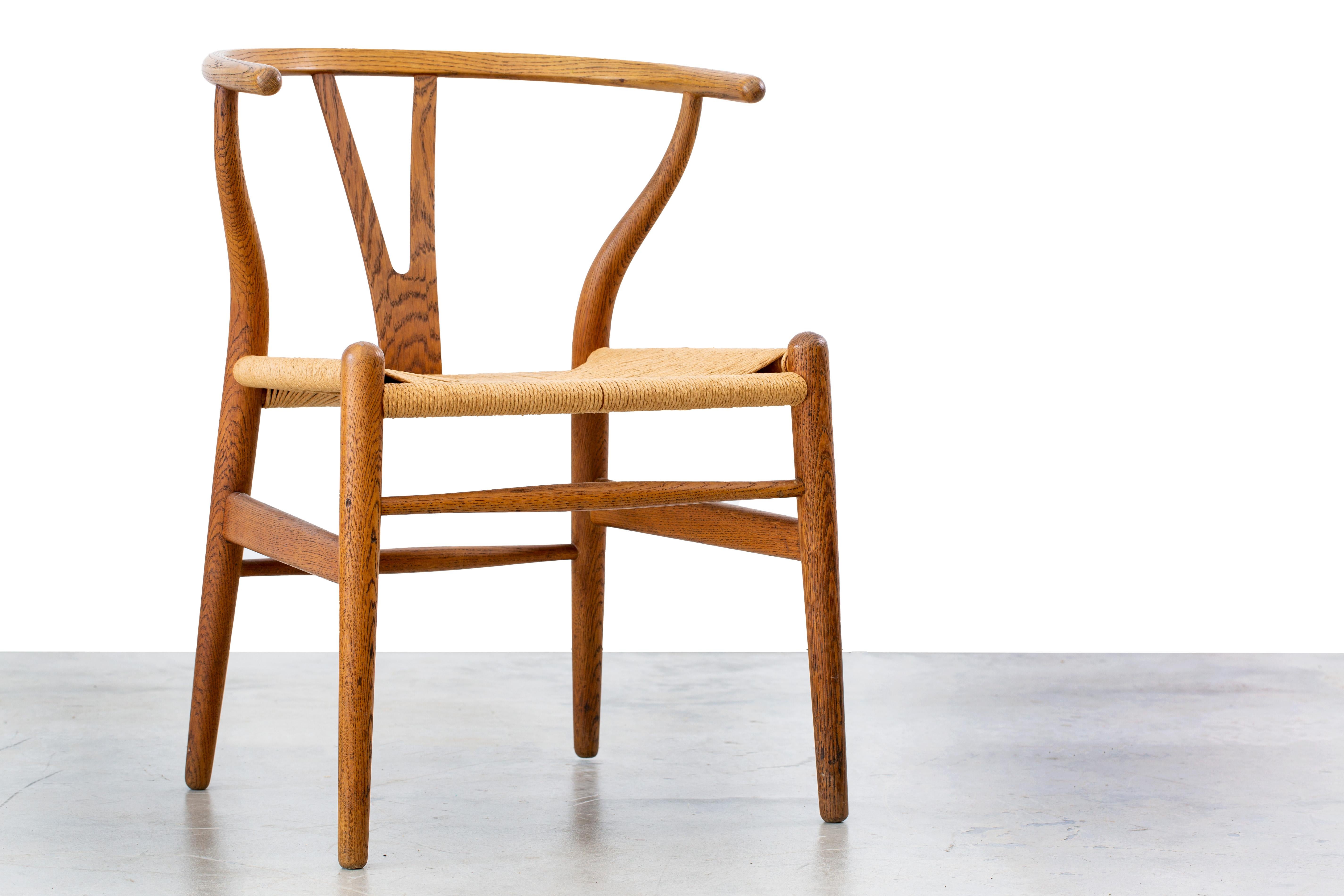 Der ikonische Querlenker-Stuhl, Modellnummer CH24, entworfen von Hans Wegner und importiert von Illums Bolighus.  Dieses Exemplar ist eine Zeitkapsel, mit originalem Eichenholz und Papierkordelsitz, alles in fantastischem Zustand.  Dieser Stuhl