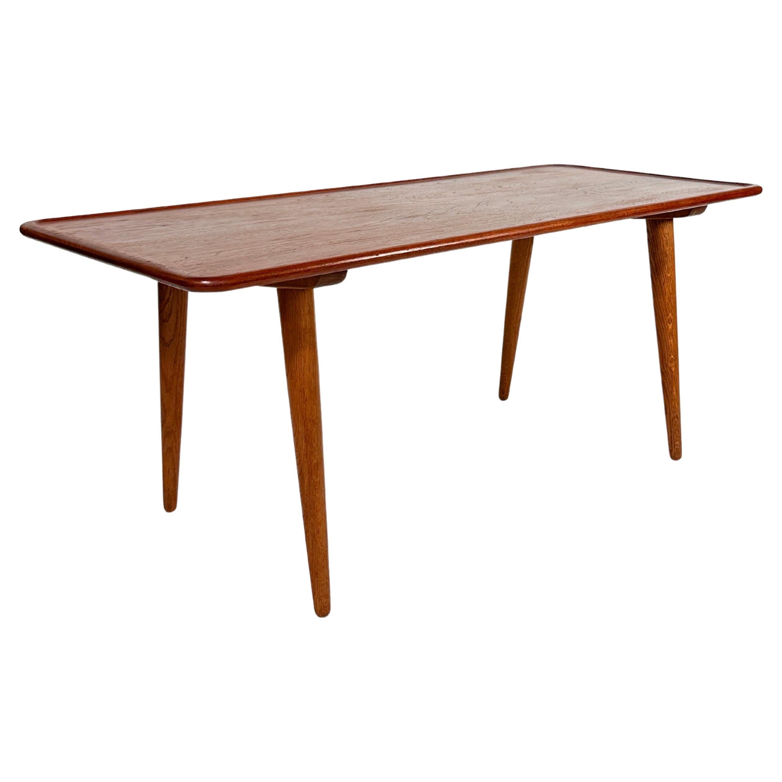 Hans Wegner coffee table, model AT-11 was designed in 1954 and produced by Andreas Tuck in Denmark. 

This version is made of a solid teak top with solid oak legs.

The wood has been cleaned, oiled and waxed. It remains a beautiful patina with a
