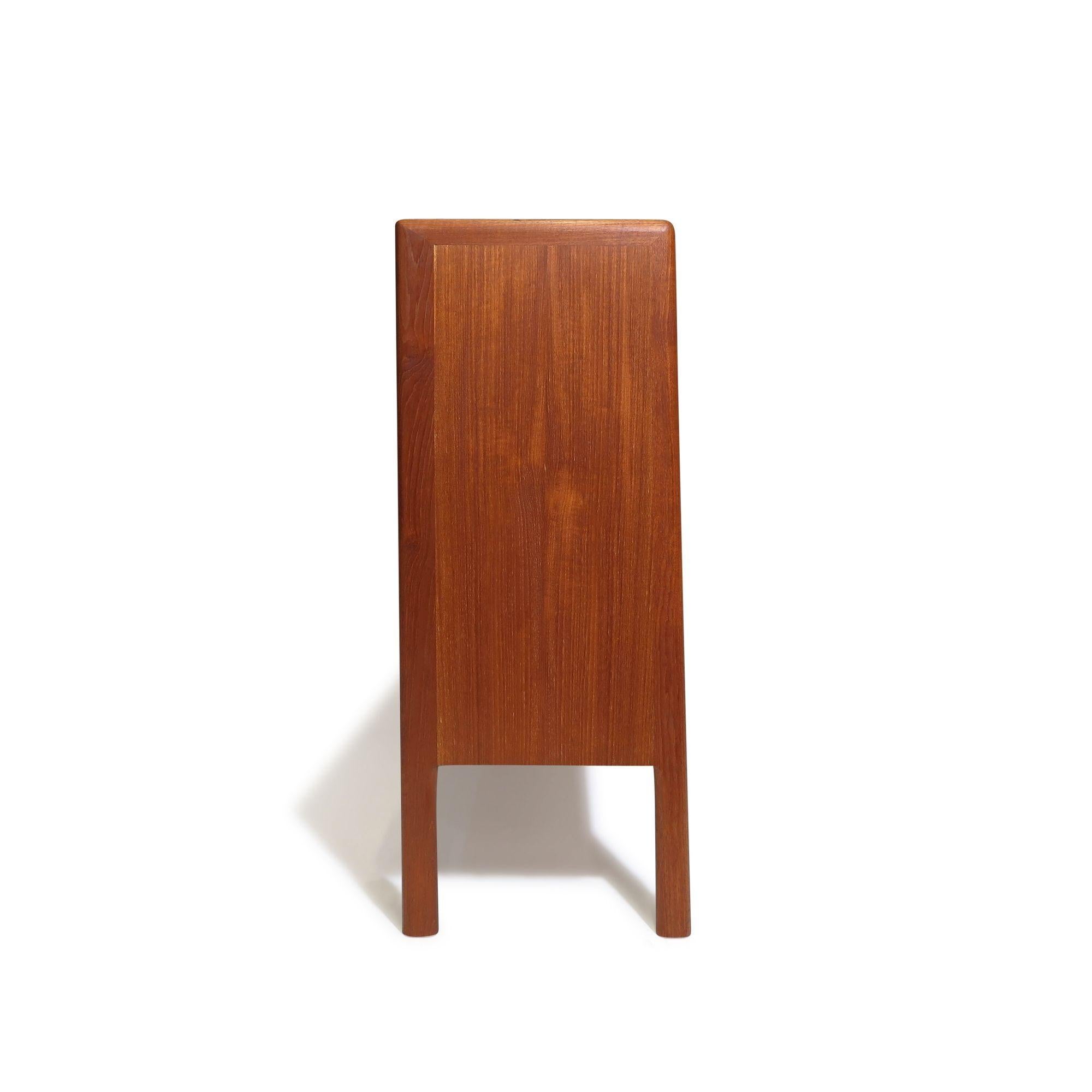 Designed by Hans Wegner, this Mid-century Danish teak cabinet features a front pair of sliding glass doors that open to reveal an interior of teak with adjustable shelves. Fully restored with a natural oil finish, the credenza highlights the rich