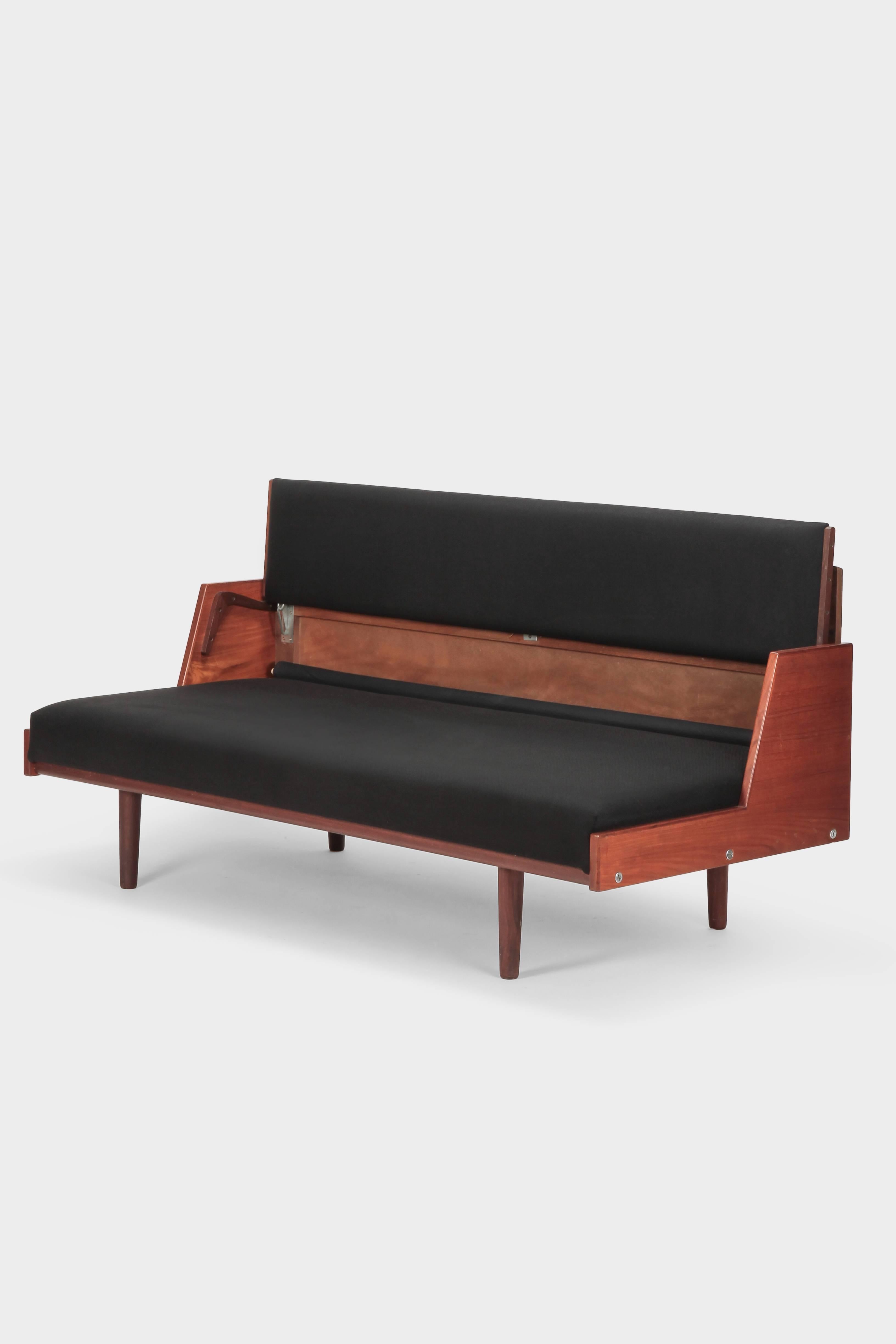 Hans Wegner daybed, model GE-258 manufactured by GETAMA in Denmark in the 1950s. This piece serves as a sofa or converts in to a guest bed. The backrest can simply be moved up and reveals an attached bed sheet to protect the upholstery.