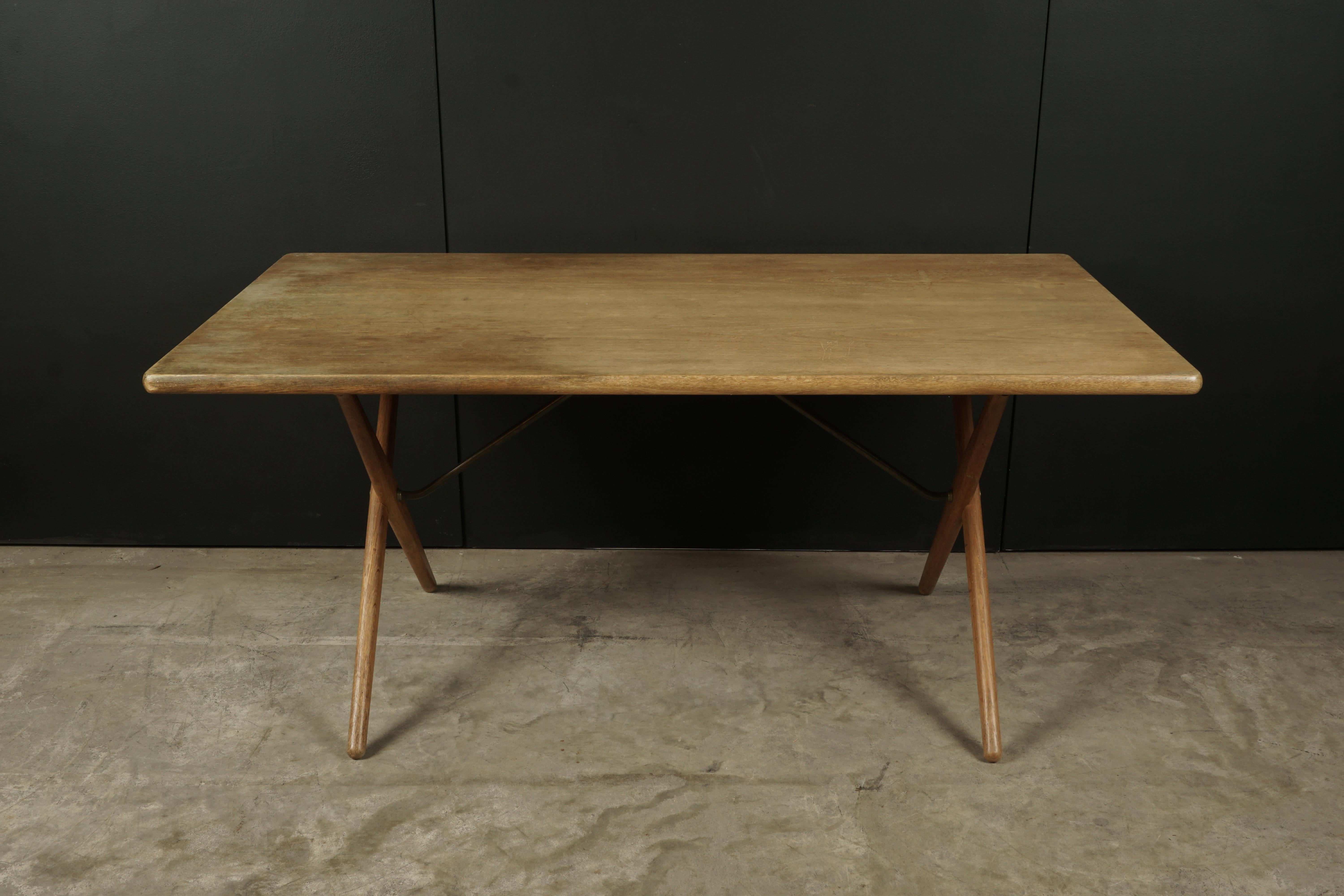 Vintage Hans Wegner AT 303 cross-leg table in oak, designed in 1955 and produced by Andreas Tuck, Denmark. Solid oak construction with brass supports on base. Nice wear and patina.