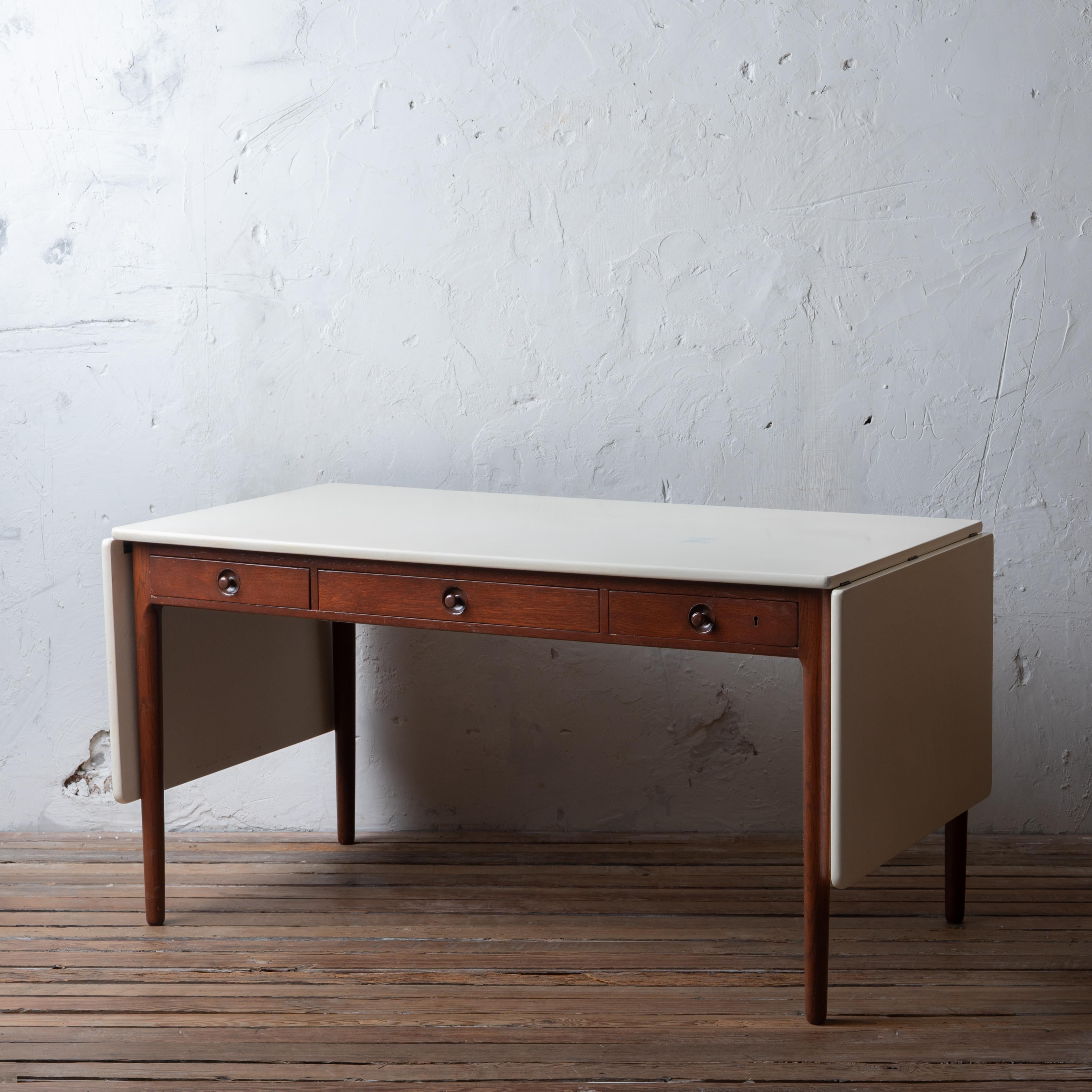 A Hans Wegner drop leaf desk or table, model AT-305 for Andreas Tuck, 1955.

The top with custom finish for an artist in a thick white water-resistant poly coating (perfect for kitchen island); base with later refinishing.

55 ¼ inches wide by 30