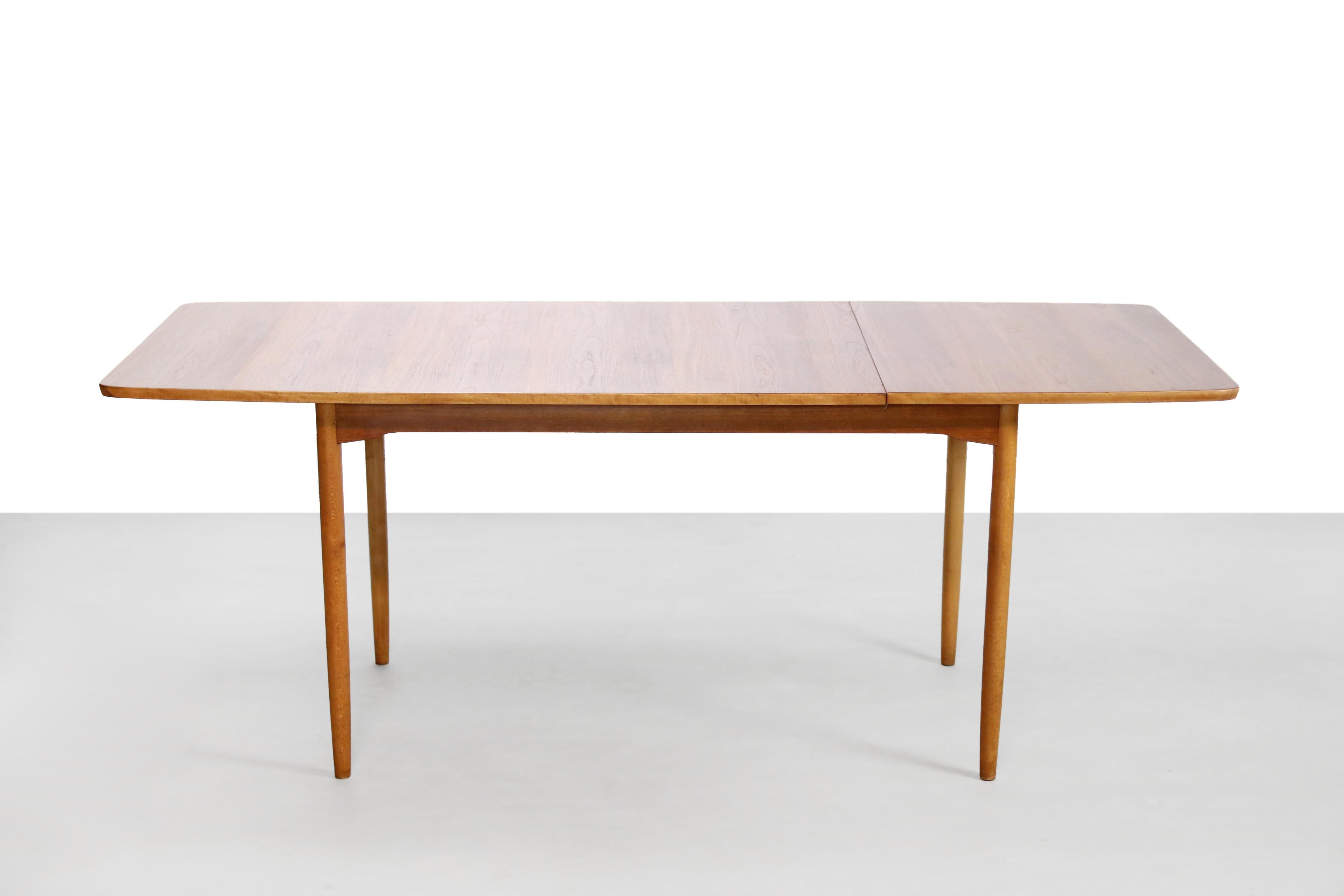 Beautiful and rare teak wooden table with beech legs which can be extended by a drop-leaf table top. By folding the top up and sliding it all the way to the left, the table can be easily extended. This table is marked the same (with die-cut numbers)