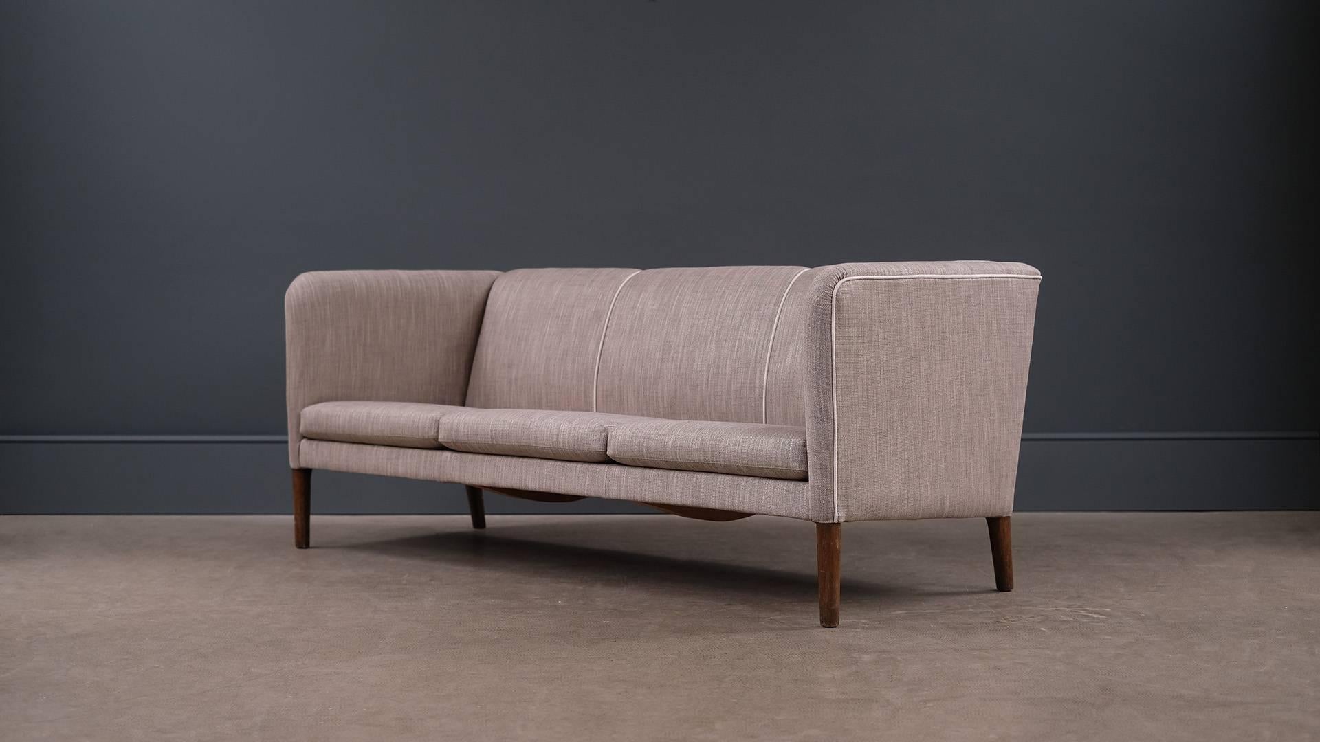 Ultra elegant Even Arm sofa designed by Hans Wegner for master cabinet maker AP Stolen, Denmark. Very comfortable sofa fully reconditioned and reupholstered in fabulous grey fabric with contrasting piping details. Great piece.