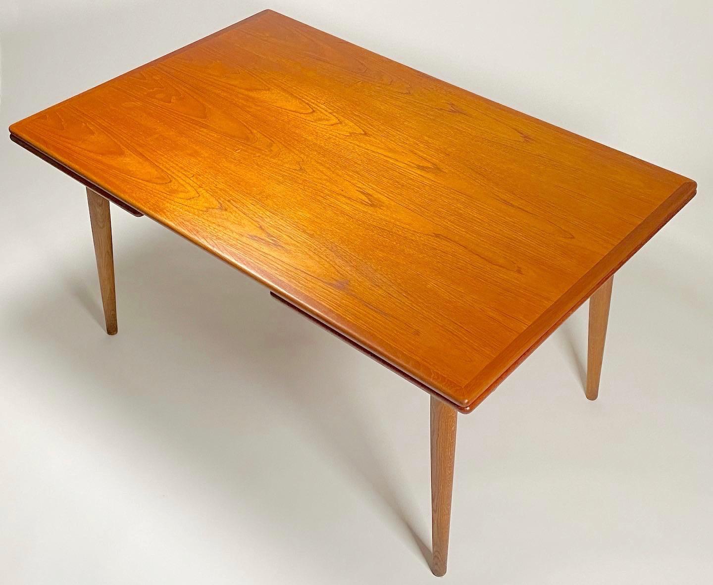 Model AT 312 teak and oak dining table by Danish architect Hans Wegner (1914-2007) for Andreas Tuck early 1950s. The table has an exceptional book matched old growth teak top with two leaves that expand the table to a total of 94.5
