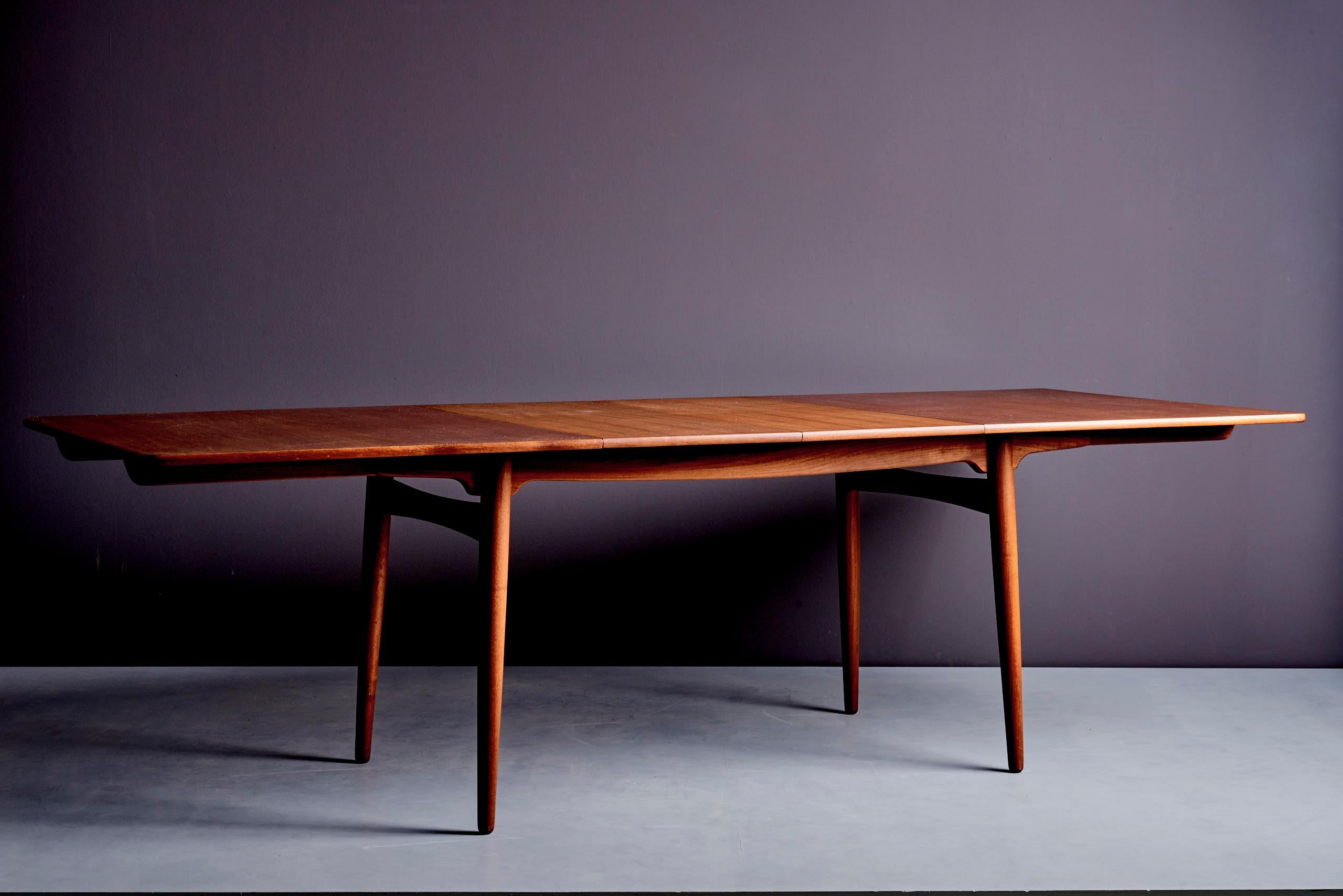 Table à rallonge en teck de Hans Wegner, fabriquée par Andreas Tuck au Danemark. La longueur totale en position déployée est de 240 cm. Lorsque les deux feuilles supplémentaires au centre sont enlevées, la table mesure 160 cm de large. L'état est