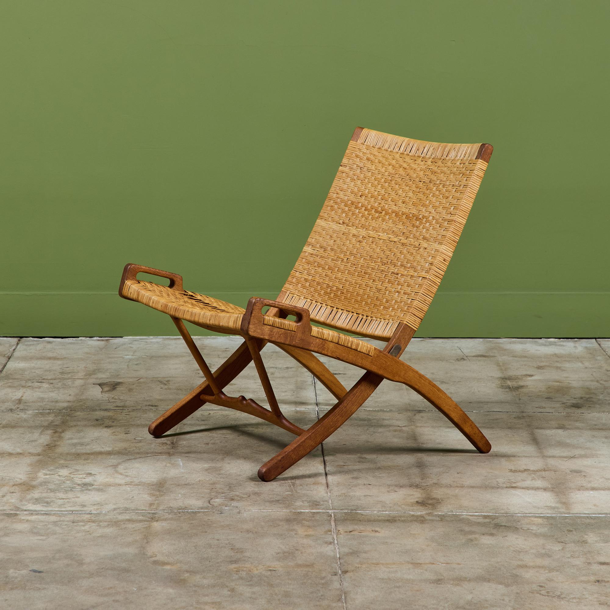 Conçue en 1949 par Hans Wegner et produite vers les années 1950 pour Johannes Hansen. La chaise cannée présente un cadre en chêne avec le cannage d'origine. L'assise de la chaise est inclinée, offrant une hauteur d'assise plus élevée vers l'avant de